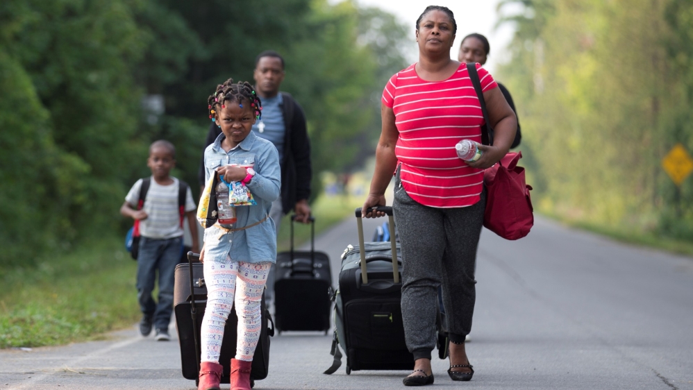 A family that stated they are from Haiti walk to the US-Canada border to cross into Canada from Champlain, New York