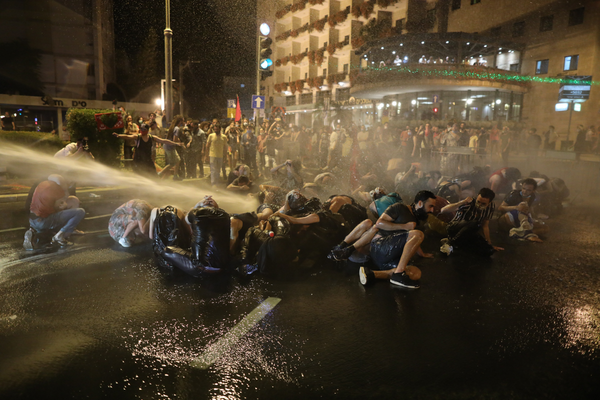 epa08546471 Israeli police use water canon to spread protesters blocking the road during a protest against Israeli prime minister Benjamin Netanyahu corruption charges, outside his residence in Jerusa
