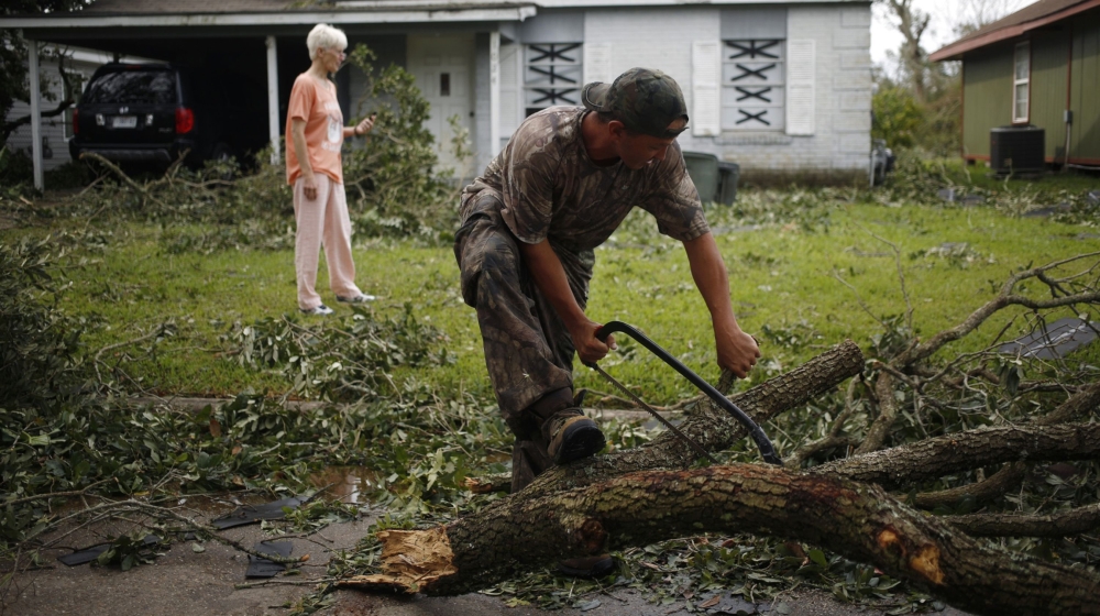 A man uses a saw to cut a tree limb downed after Hurricane Laura made landfall in Lake Charles, Louisiana, U.S., on Thursday, Aug. 27, 2020. Hurricane Laura raked across Louisiana early on Thursday, b