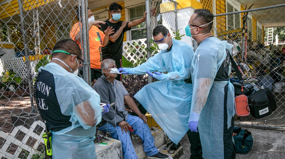An EMS medic checks the temperature of a possible Covid-9 patient before transporting him to the hospital on August 13, 2020 in Houston, Texas. Several of the man's family members had also tested posi