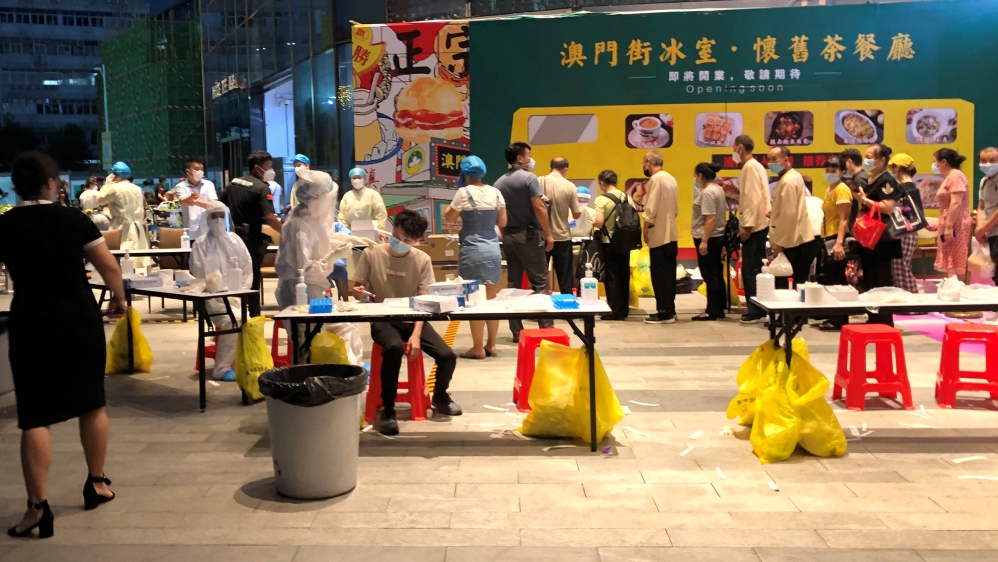 Medical workers wearing protective suits are seen at a nucleic acid testing site outside the IBC Mall in Shenzhen