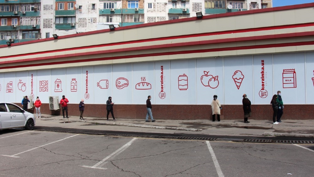 People wearing protective face masks line up at a safe social distance outside the grocery store amid the coronavirus disease (COVID-19) outbreak in Tashkent, Uzbekistan