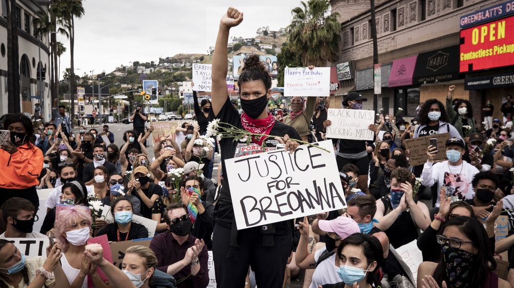 A protester raises her fist while holding a placard reading 'Justice for Breonna' during a gathering to celebrate the birthday of Breonna Taylor amid demonstrations over the arrest in Minnesota of Geo