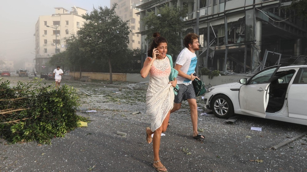 People run for cover following an explosion in Beirut's port area