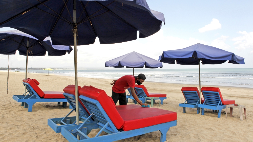 A worker cleans chairs for rent as beaches are reopening following months of lockdown due to the new coronavirus outbreak, in Bali, Indonesia, Monday, July 27, 2020. The Indonesia Health ministry anno