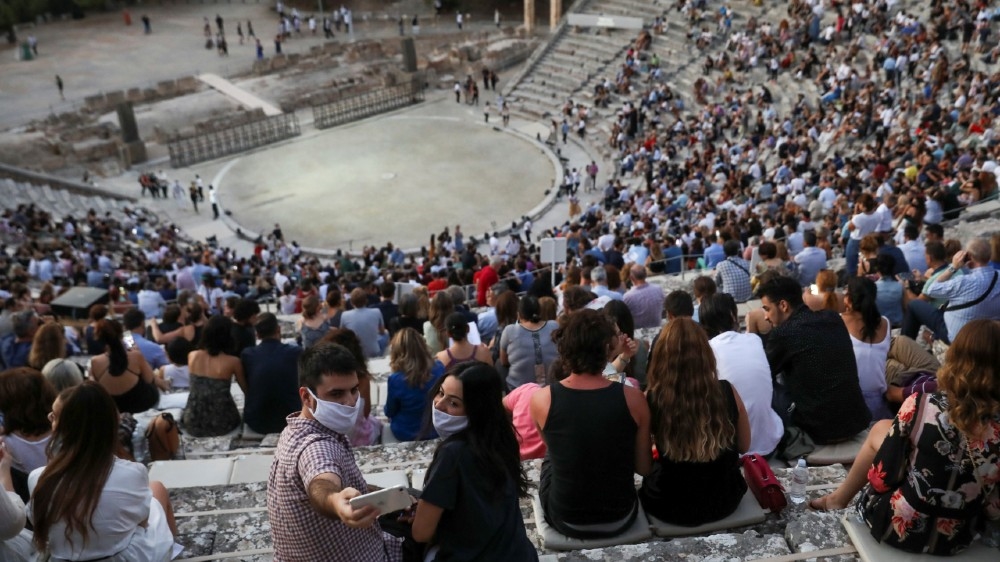 People wearing protective face masks take a selfie as they wait for the start of 