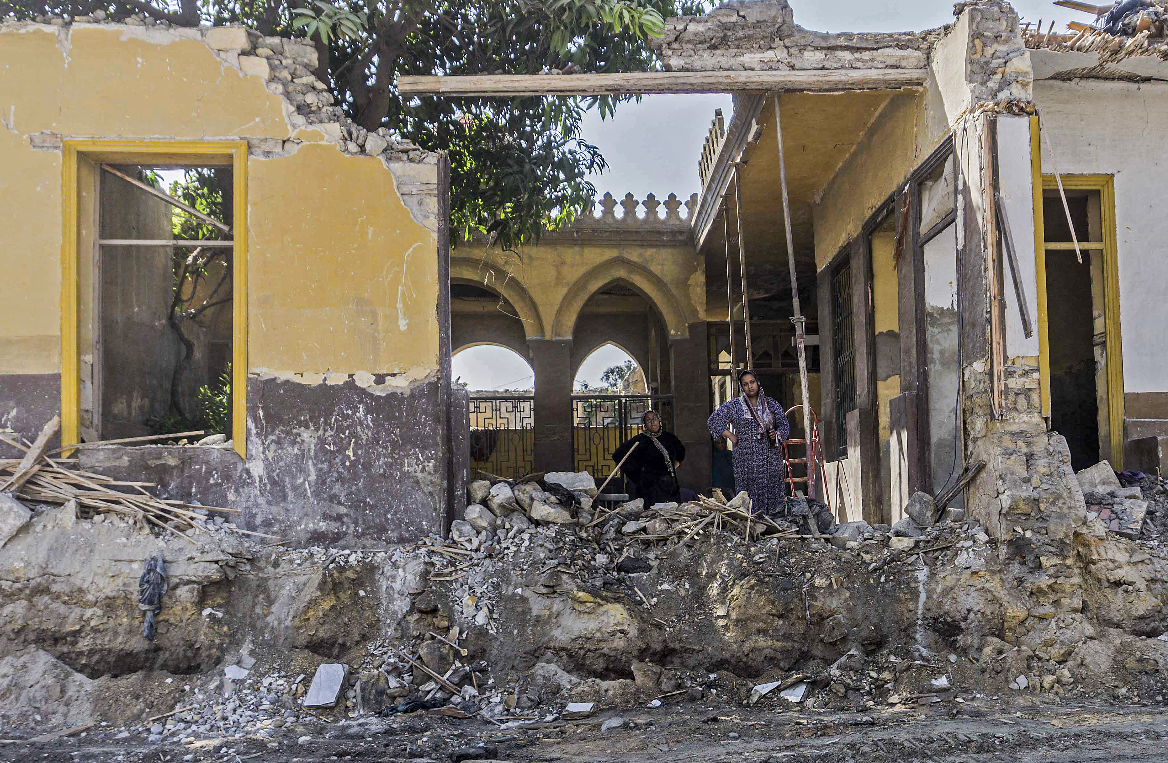 Women residents of a cemetery undergoing demolition stand in the rubble amidst ongoing roadworks at the historic City of the Dead necropolis of Egypt's capital Cairo