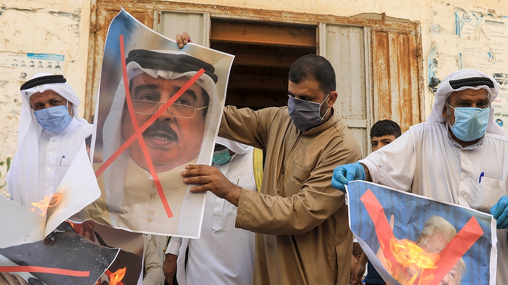 Palestinian men burn the exed out portraits of the Bahraini King, US President and Israeli Premier during a protest in Deir al-Balah, in central Gaza Strip, on September 12, 2020, to condemn the norma
