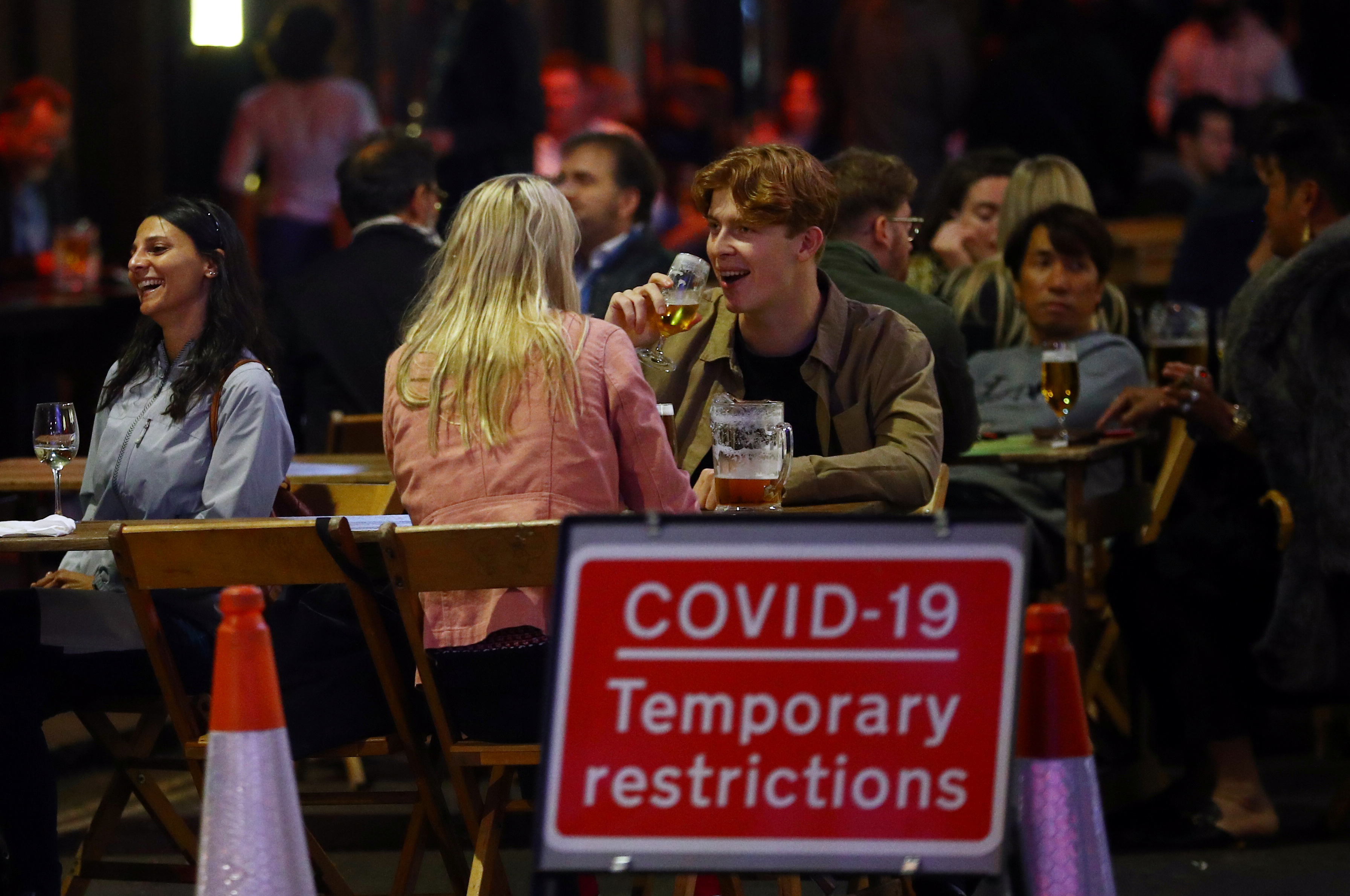 People sit at the tables outside restaurants in Soho, amid the outbreak of the coronavirus disease (COVID-19), in London