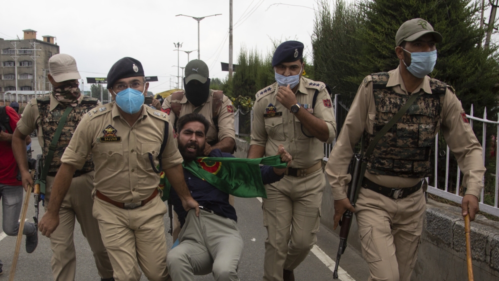 Indian policemen detain a Kashmiri Shiite Muslims as he and others