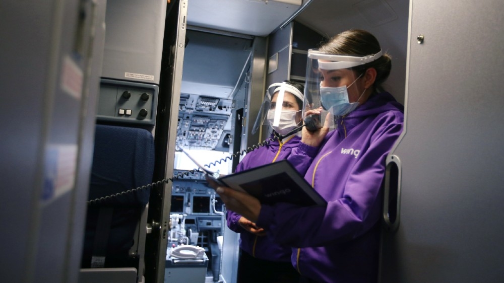 Employees of Wingo Airlines wearing face shields and protective masks are seen inside an airplane at the El Dorado International Airport, amidst the coronavirus disease (COVID-19) outbreak,