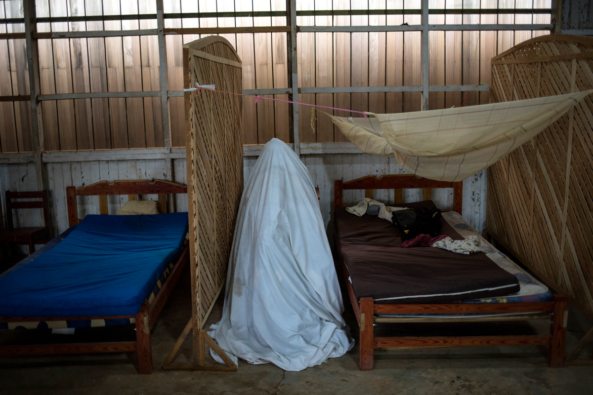 Sara Magin, who suffers from COVID-19 symptoms, sits inside a tent constructed from a bedsheet as she receives an herbal vapor therapy, at the Comando Matico headquarters, in the Shipibo Indigenous co