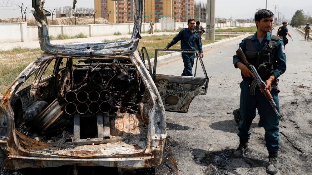 Afghan police officers inspect a vehicle from which insurgents fired rockets, in Kabul