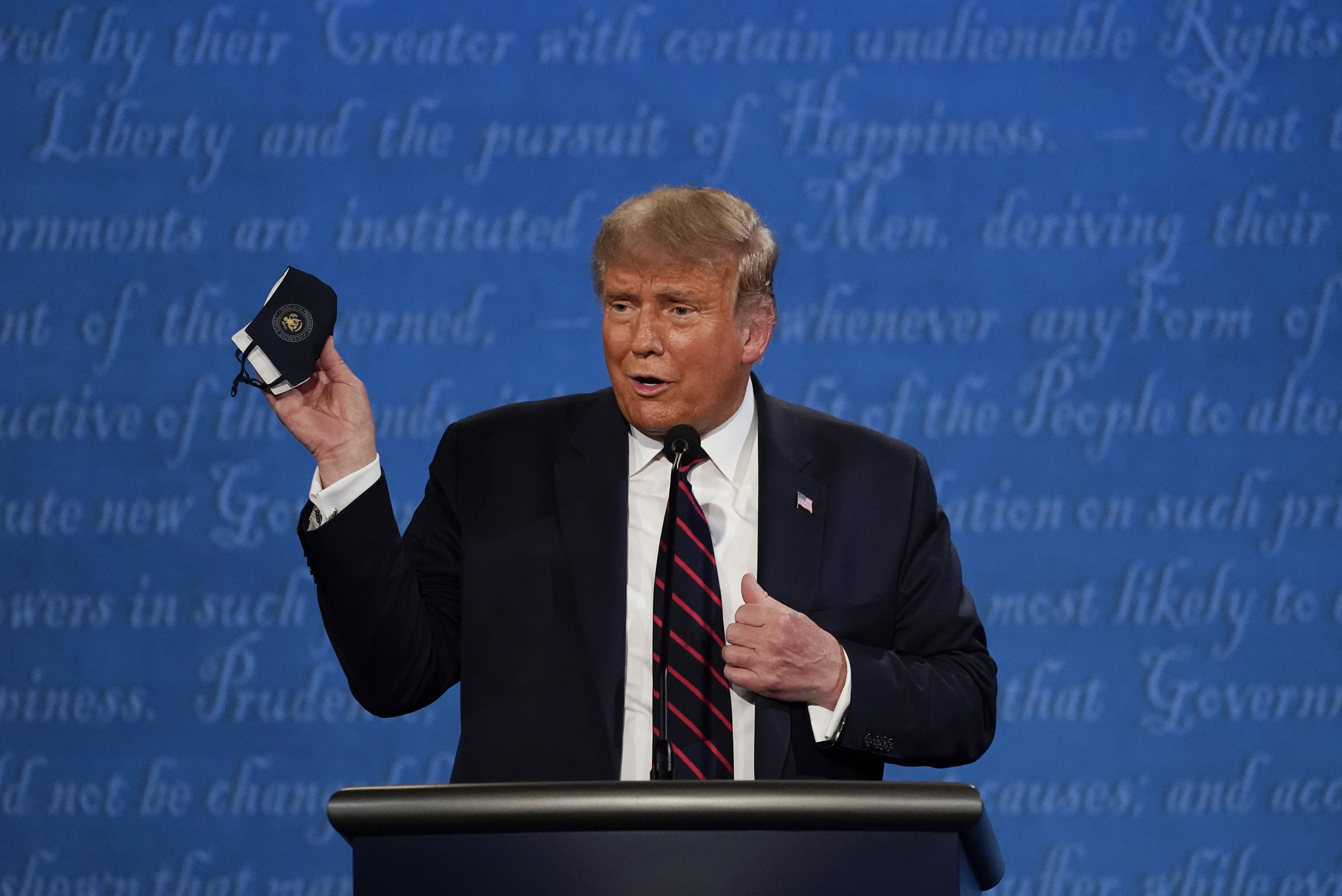 President Donald Trump holds up his face mask during the first presidential debate. He later tested positive for COVID-19 [File: AP Photo/Julio Cortez]