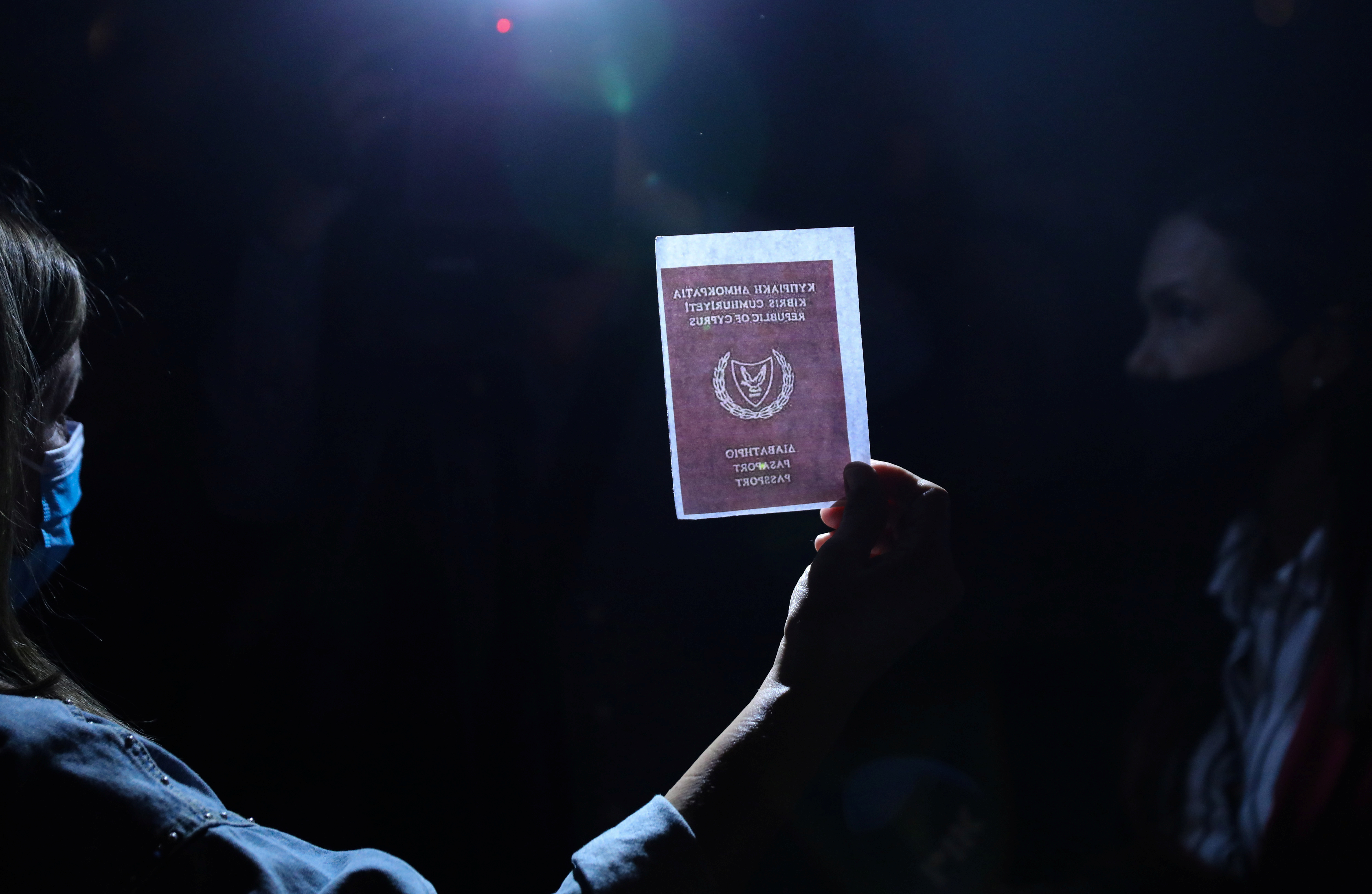 A person holds an image of a passport during a protest against corruption outside the Filoxenia Conference Center, currently hosting Cyprus parliament, in Nicosia, Cyprus October 14, 2020. [Yiannis Kourtoglou/Reuters]