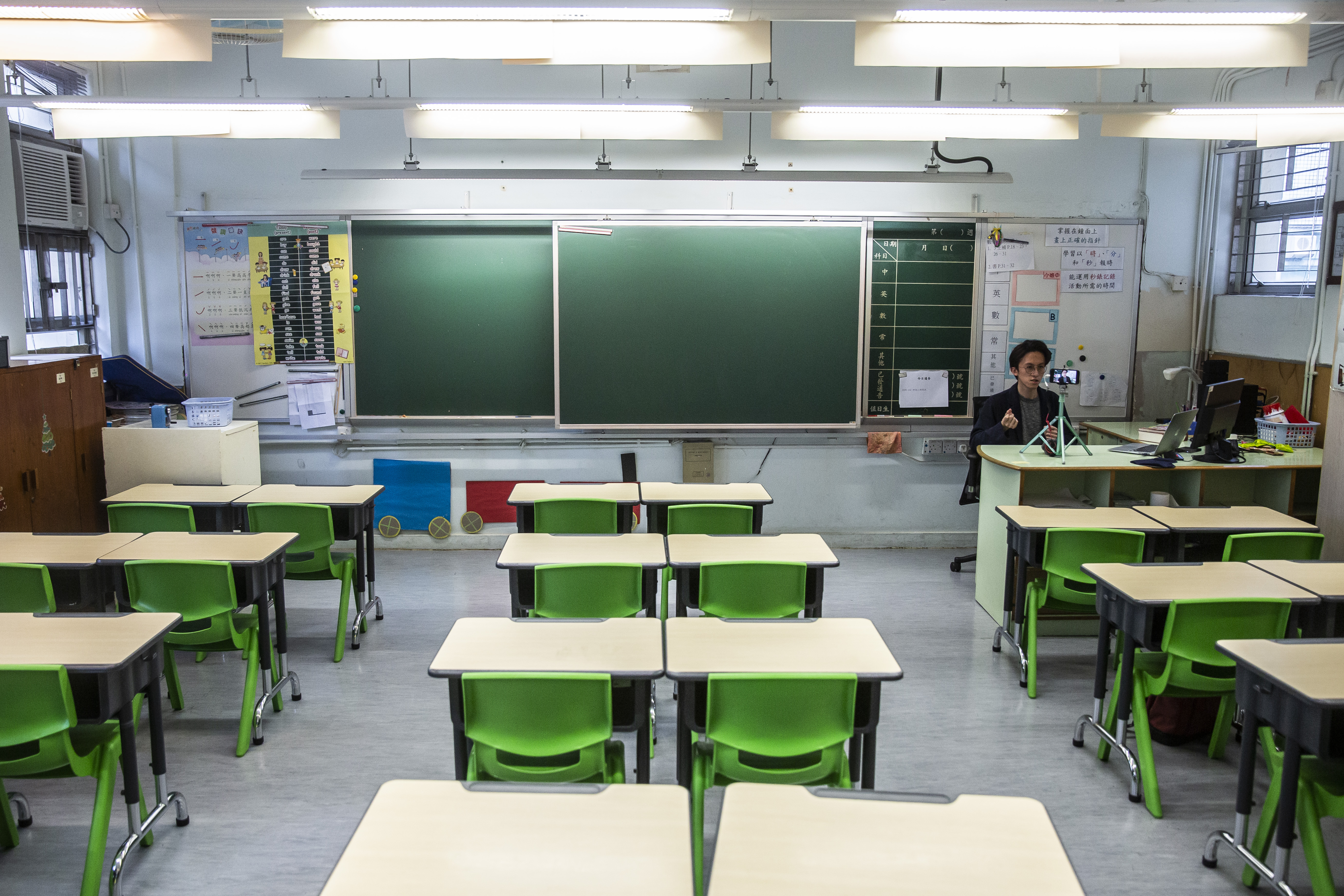 A primary school teacher records a video lesson for his students who have had their classes suspended due to the COVID-19 pandemic, in his empty classroom in Hong Kong, March 6, 2020 [Isaac Lawrence/AFP]