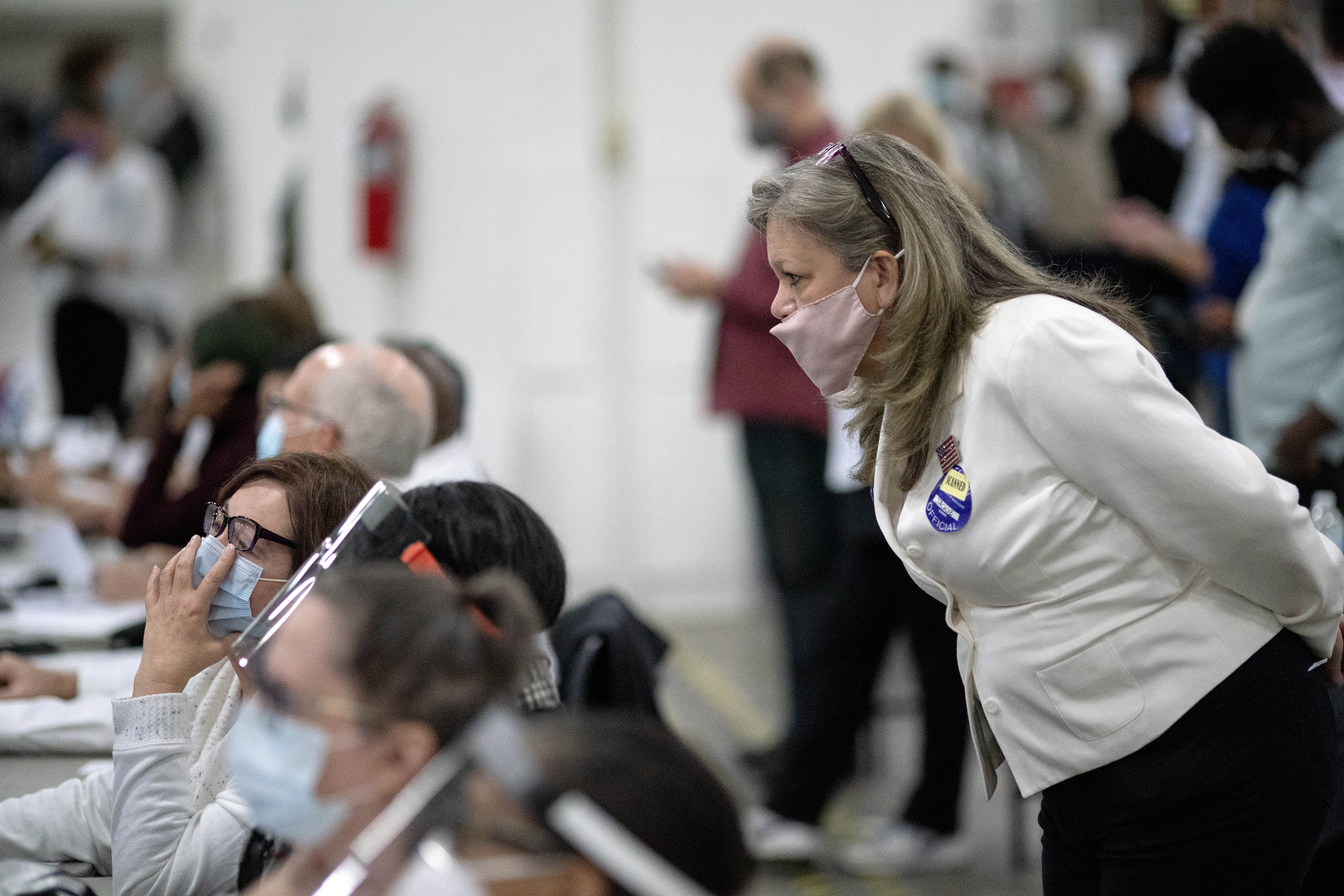 A Republican election challenger at right watches over election inspectors as they examine a ballot as votes are counted into the early morning hours Wednesday, November 4, 2020, at the central counting board in Detroit. (AP Photo/David Goldman)