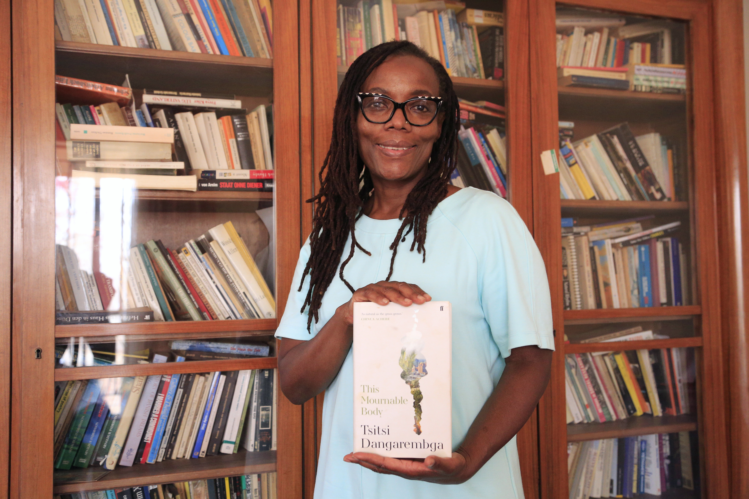 Tsitsi Dangarembga with a copy of her book, This Mournable Body, at her home in Harare, Zimbabwe [Aaron Ufumeli/EPA]