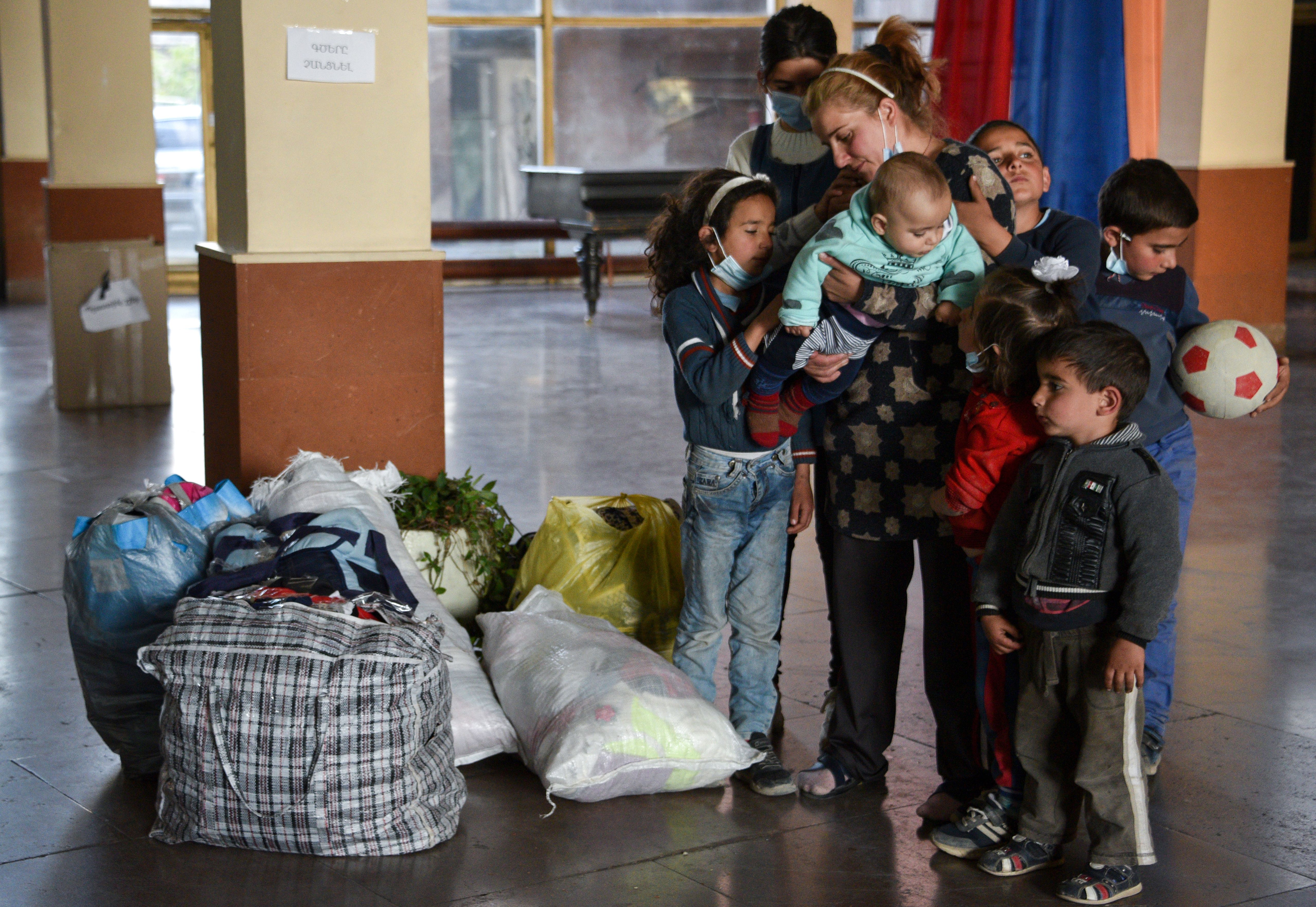 Zhanna Petrosyan (35), a refugee from the village of Tsapatagh of the Nagorno-Karabakh region and her seven children stand next to their belongings at a centre for refugees, in Yerevan, on October 24, 2020 after fleeing fierce fighting in the Nagorno-Karabakh region. File: AFP/Karen Minasyan]