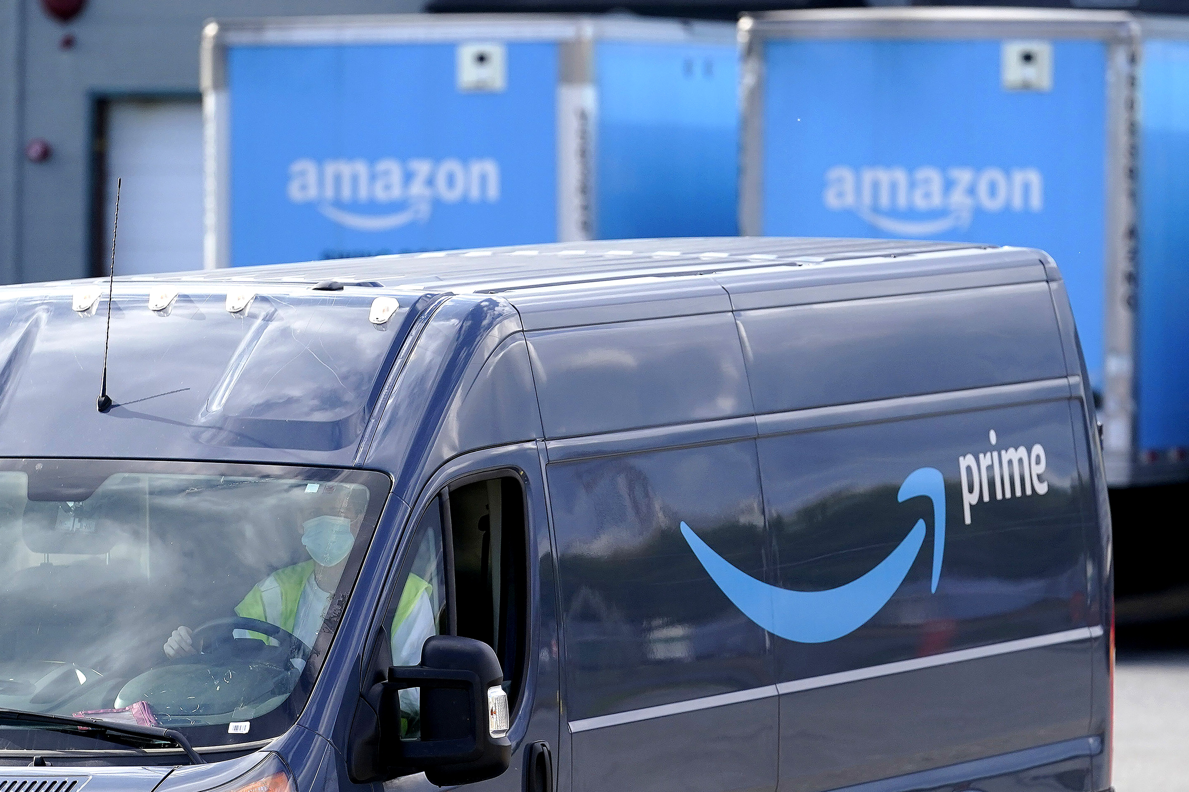 an Amazon Prime logo appears on the side of a delivery van as it departs an Amazon Warehouse location in Dedham, Mass., US