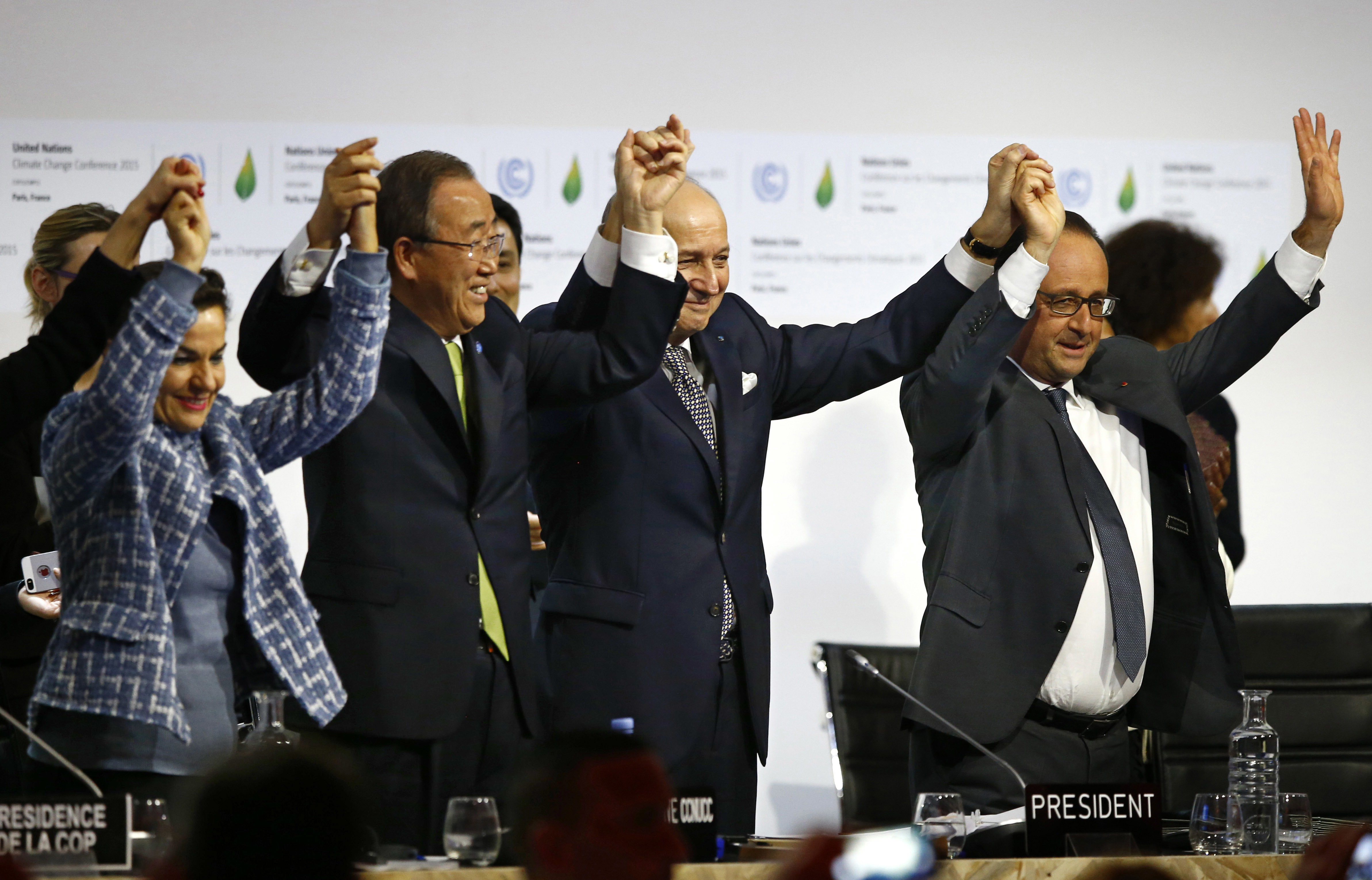 In this photo from December 12, 2015, in Paris, French President Francois Hollande, right, French Foreign Minister and president of COP21 Laurent Fabius, second right, UN climate chief Christiana Figueres, left, and UN Secretary-General Ban Ki-moon hold their hands up in celebration after the final conference at COP21, which culminated in the Paris climate agreement