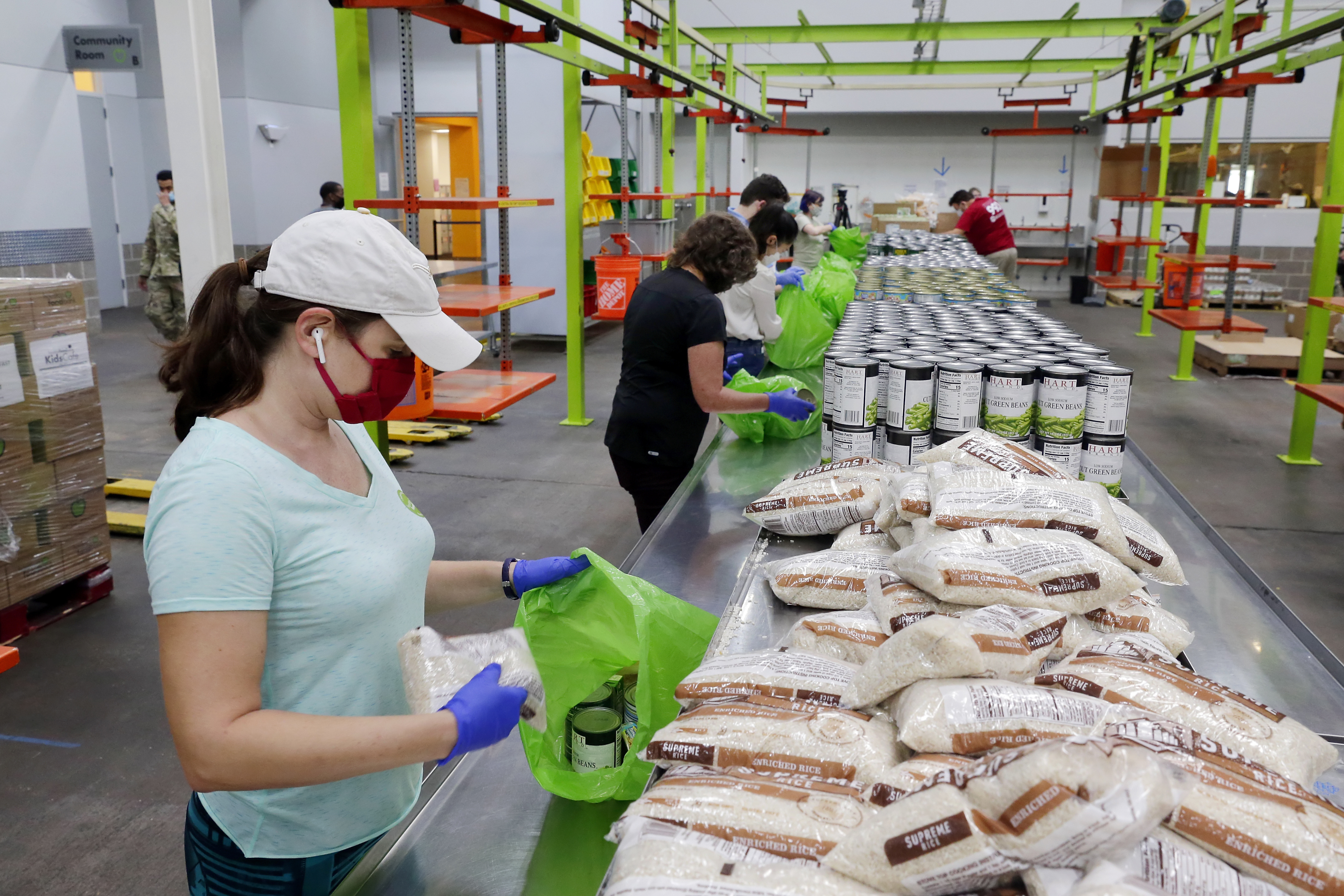 Volunteers load non perishable foods in green grocery bags for a school student food programme at the Houston Food Bank in Houston, US on October 14, 2020 [File: AP/Michael Wyke]