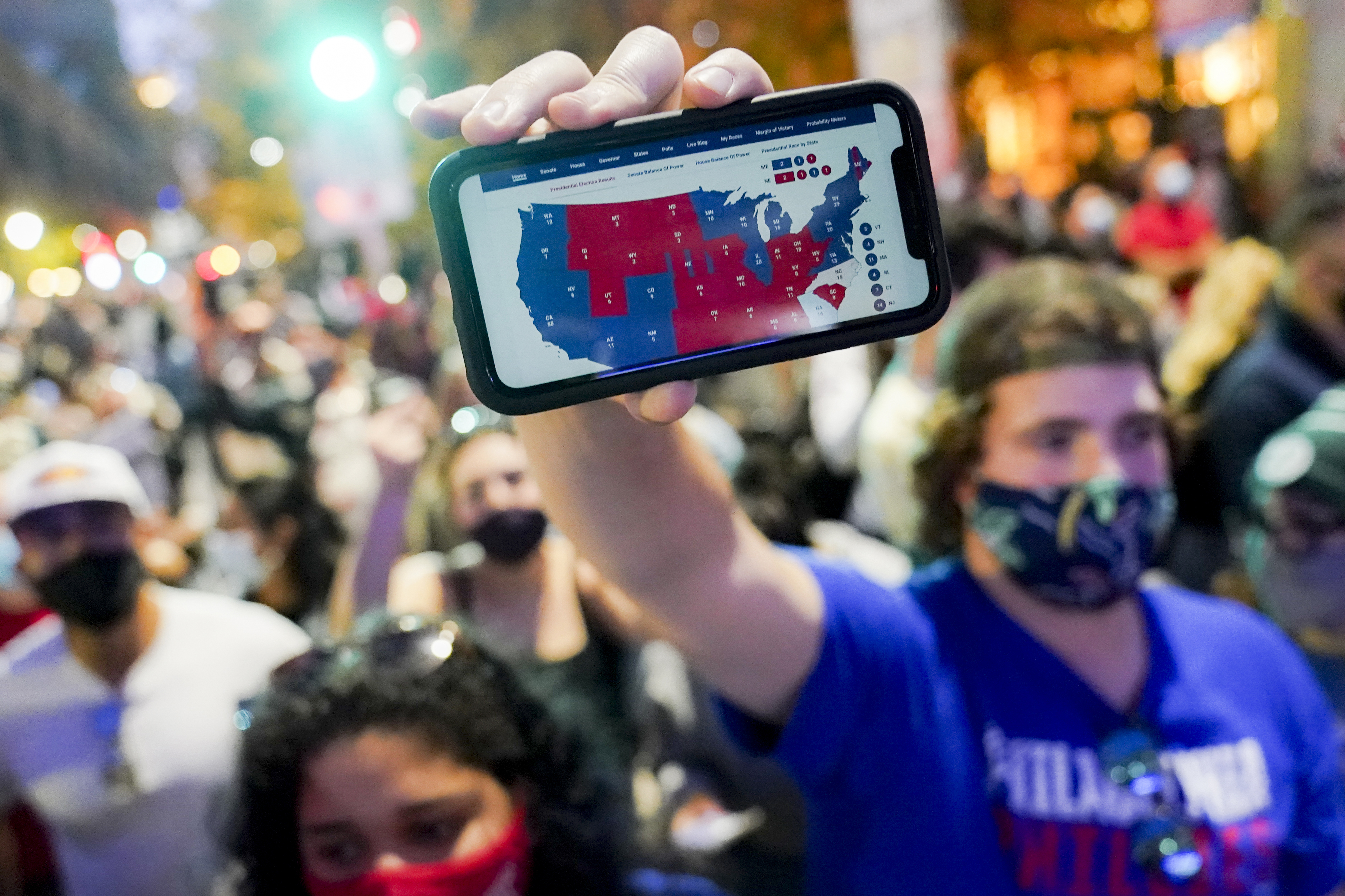A supporter of President-elect Joe Biden holds up his mobile phone to display the electoral college map after the 2020 Presidential Election is called, November 7, 2020, in Philadelphia [John Minchillo/AP Photo]