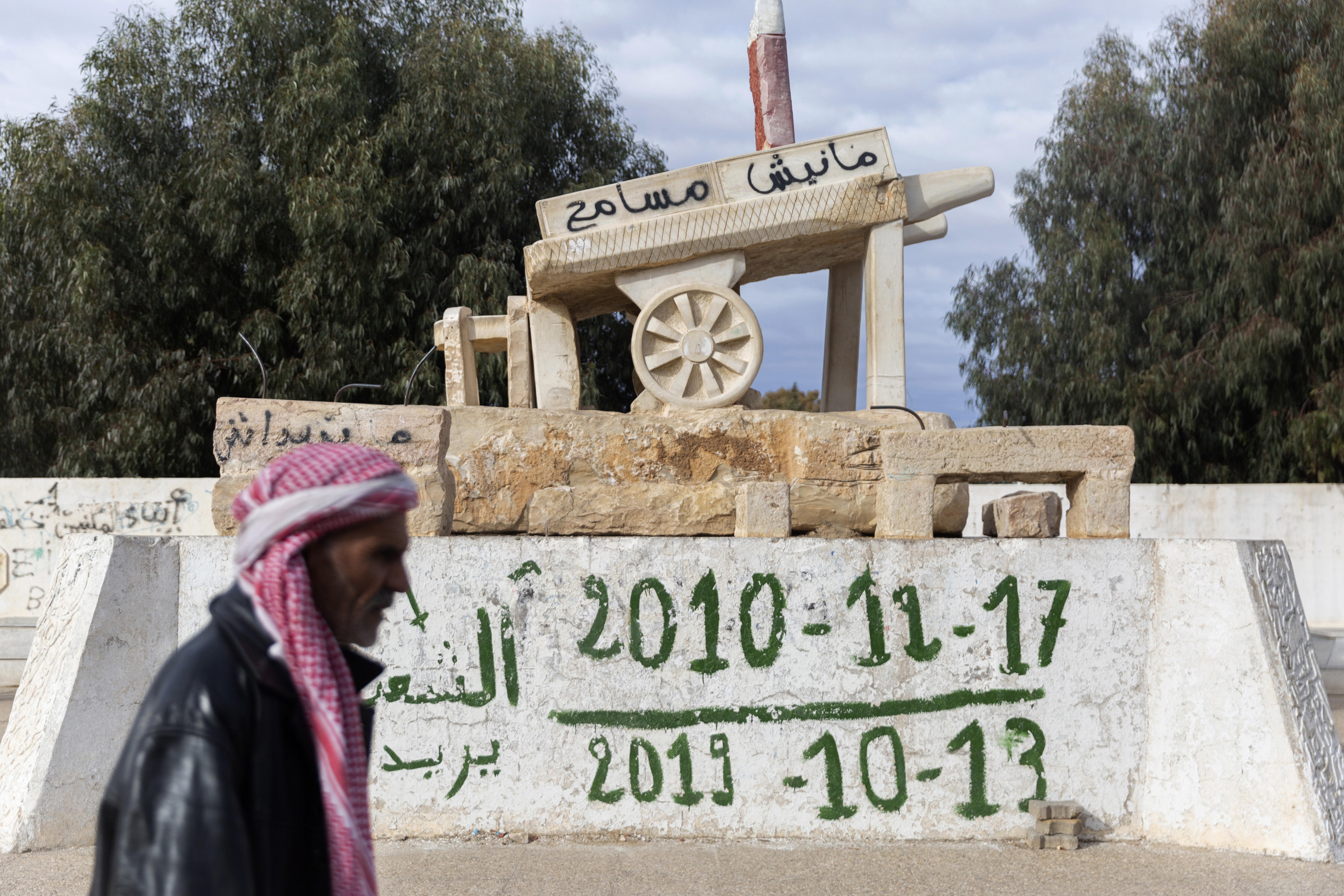 A man walks past a statue of the chariot of Mohamed Bouazizi, the 26-year-old fruit seller whose self-immolation in 2010 led to the downfall of Tunisia’s dictator of 23 years and unleashed the Arab Spring uprisings across the region. Sidi Bouzid, Tunisia, Dec 11, 2020. [AP Photo/Riadh Dridi]