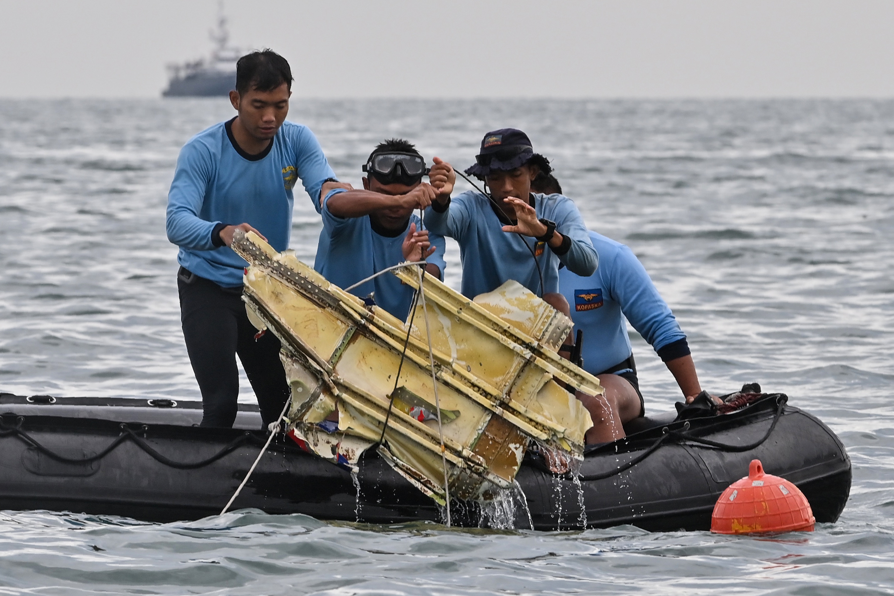 Indonesian Navy divers hold wreckage from Sriwijaya Air flight SJY182 during a search and rescue operation at sea near Lancang island on January 10, 2021, after the Boeing 737-500 crashed shortly after taking off from Jakarta airport on January 9. (Photo by ADEK BERRY / AFP)
