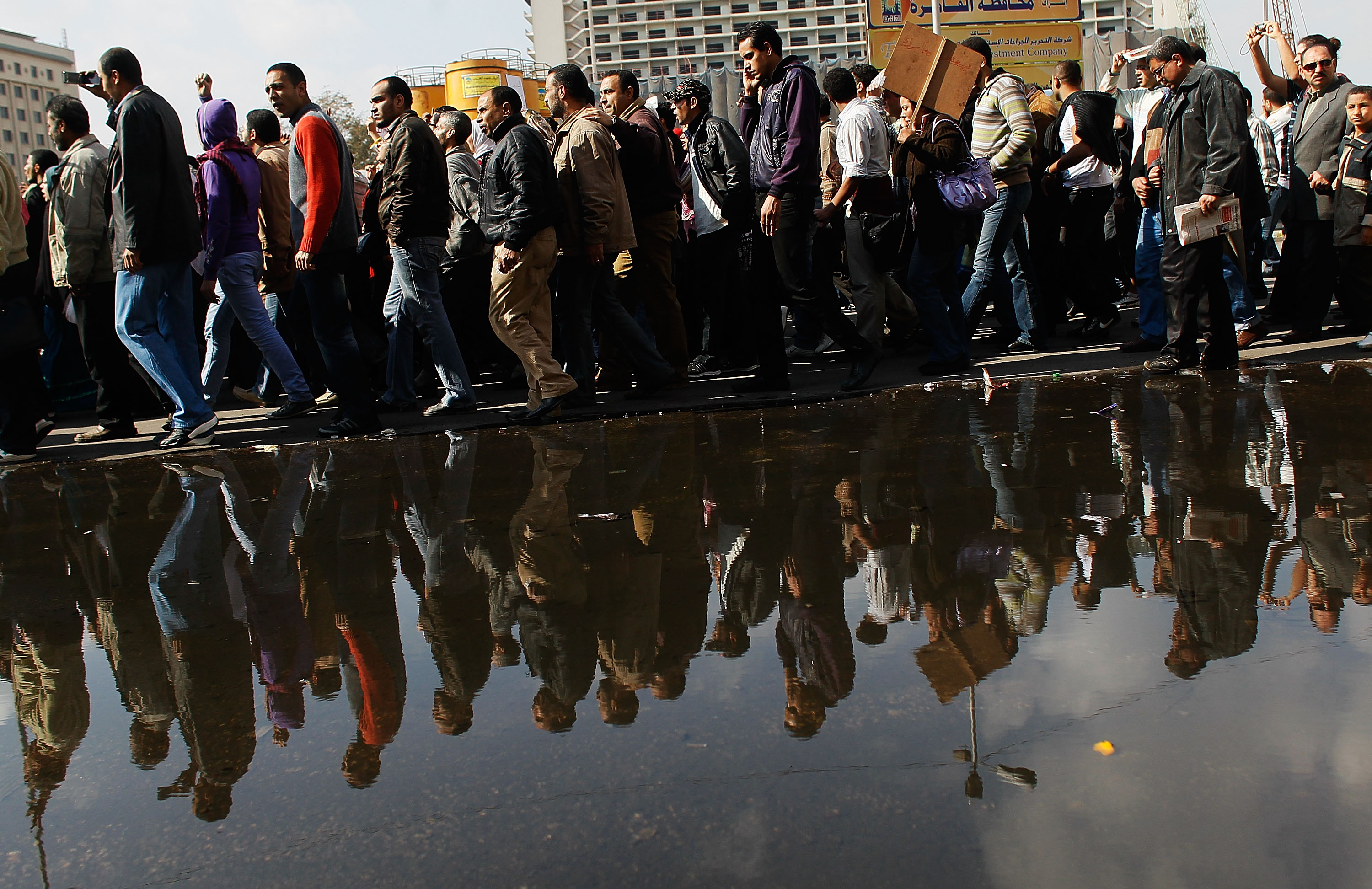 A crowd of anti-government protesters walk past a large puddle of water from tapped water mains in Tahrir Square on the morning of January 31, 2011 in central Cairo, Egypt [Chris Hondros/Getty Images]