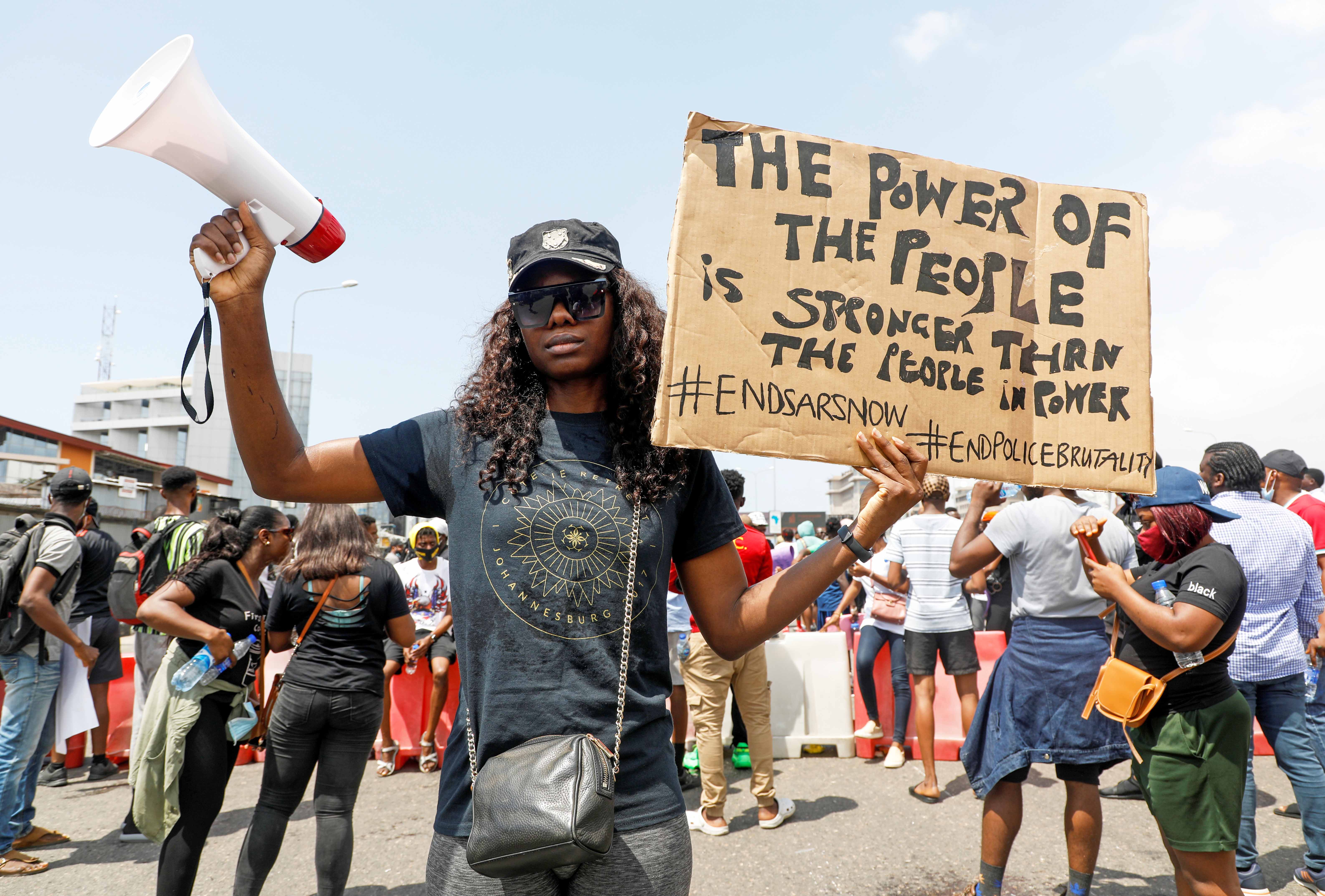 A demonstrator holds a banner during a protest against alleged police brutality in Lagos on October 12, 2020 [File: Temilade Adelaja/Reuters]