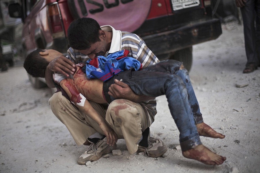 A Syrian man cries while holding the body of his son near Dar Al Shifa Hospital in Aleppo. The boy was killed by the Syrian army [File: Manu Brabo/AP Photo]