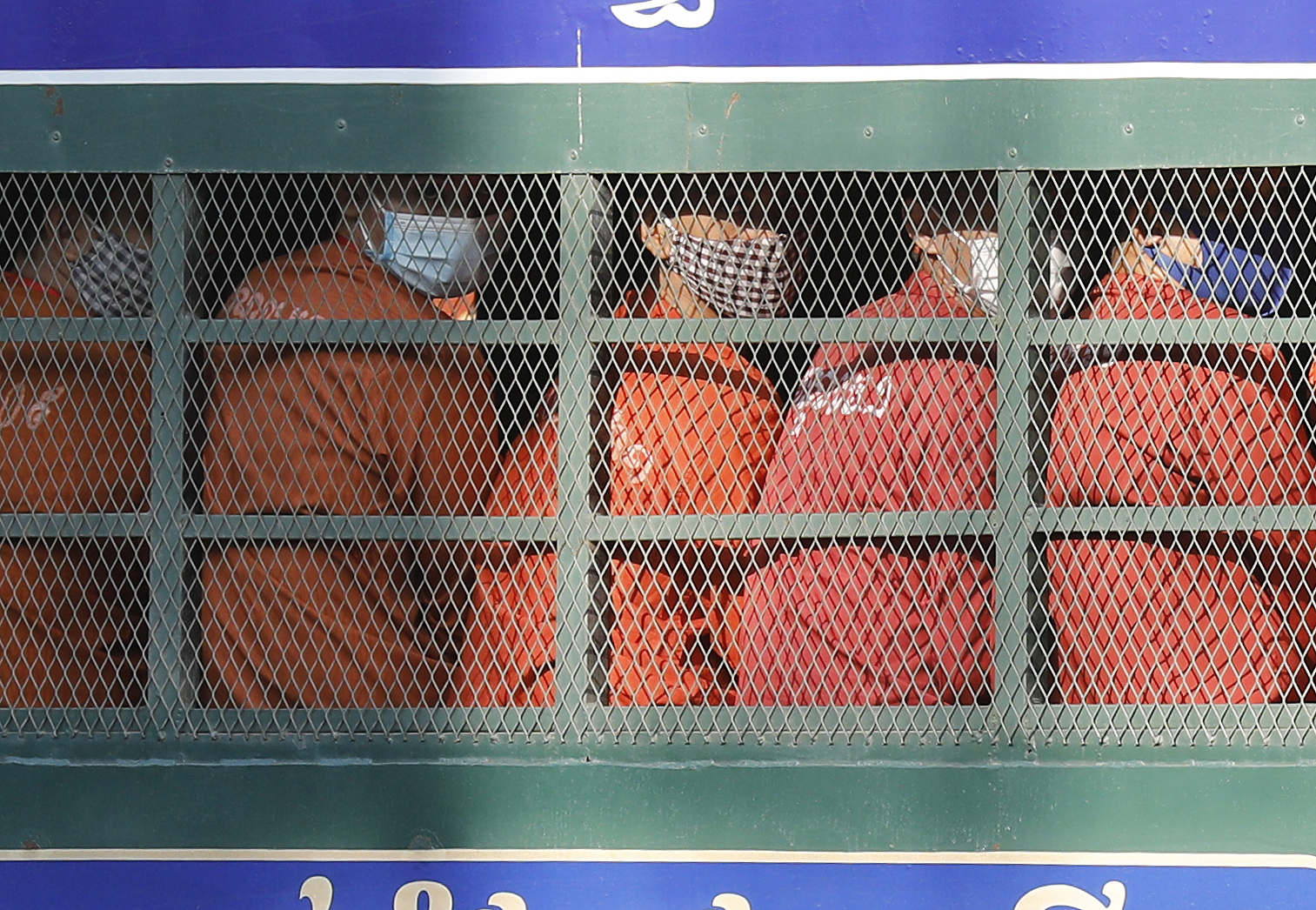 Dressed in orange prison uniforms and seated shoulder to shoulder in an open but barred, prison van, dozens of former opposition activists are brought to court