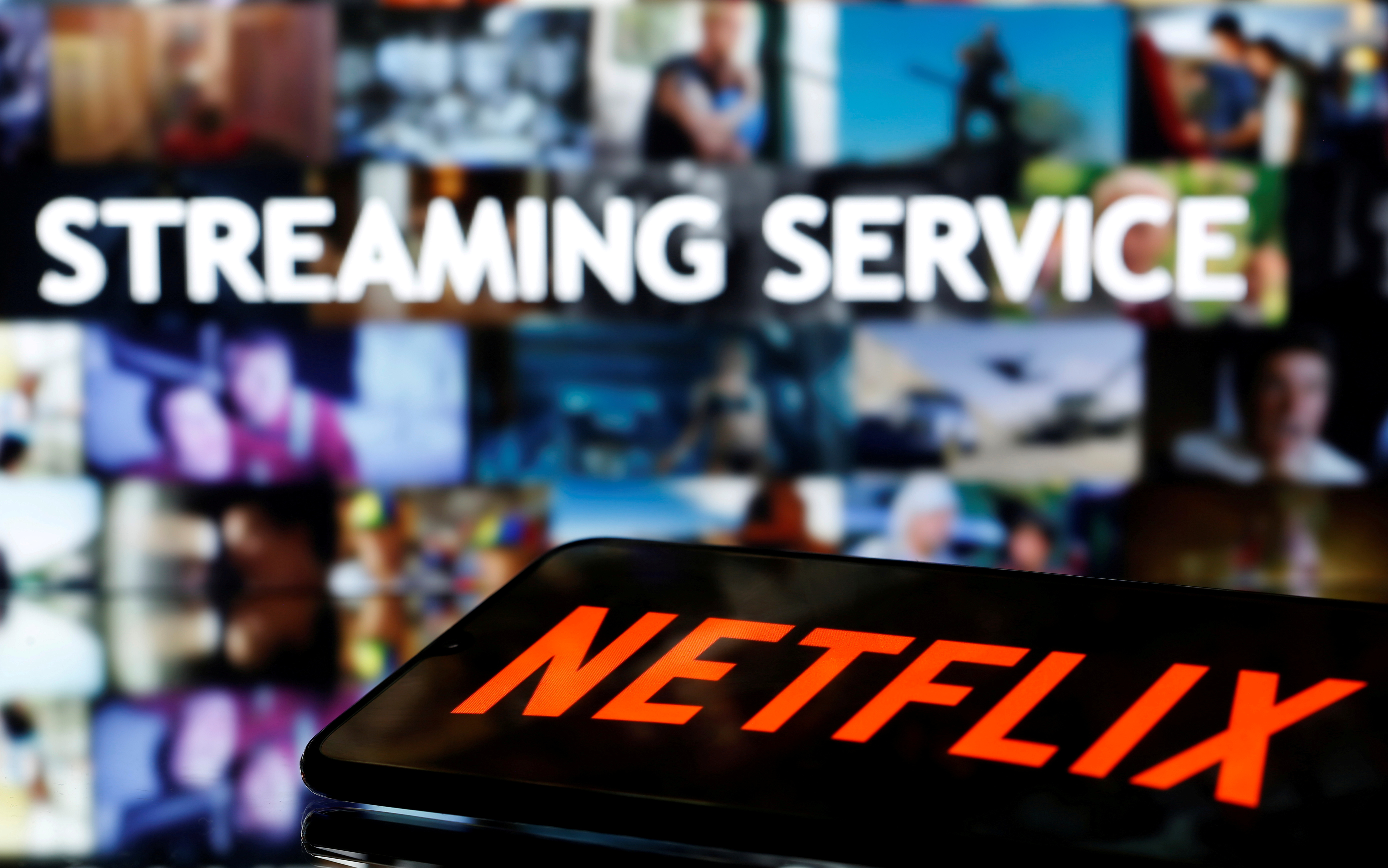 A smartphone with the Netflix logo lies in front of displayed "Streaming service" words in this illustration taken March 24, 2020. REUTERS/Dado Ruvic/Illustration/File Photo GLOBAL BUSINESS WEEK AHEAD
