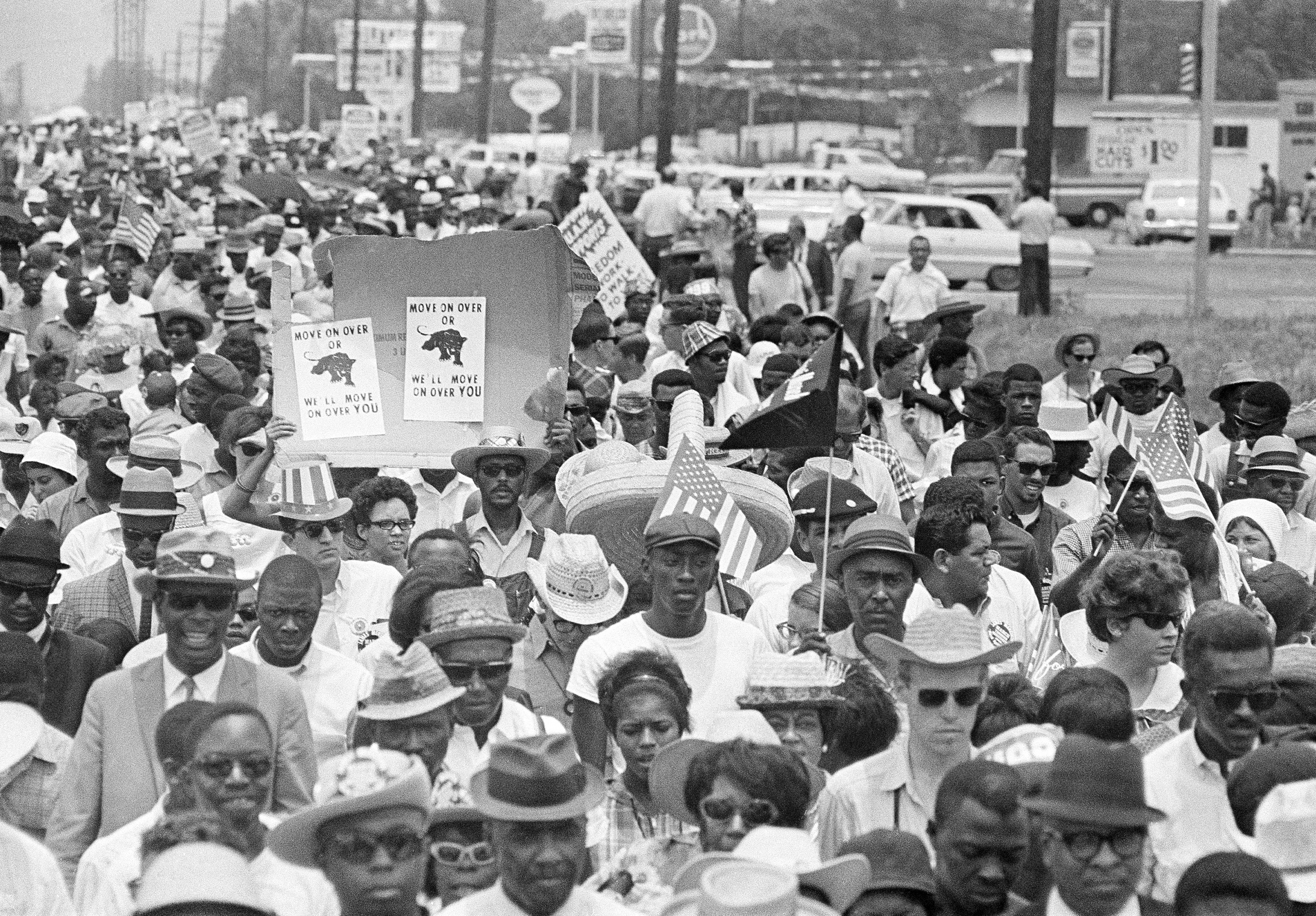 Marchers enter Jackson, Mississippi as part of the March Against Fear on June 26, 1966; two protesters hold signs of the Black Panther party that read 'Move on over or we'll move on over you' [Charles Kelly/AP Photo]