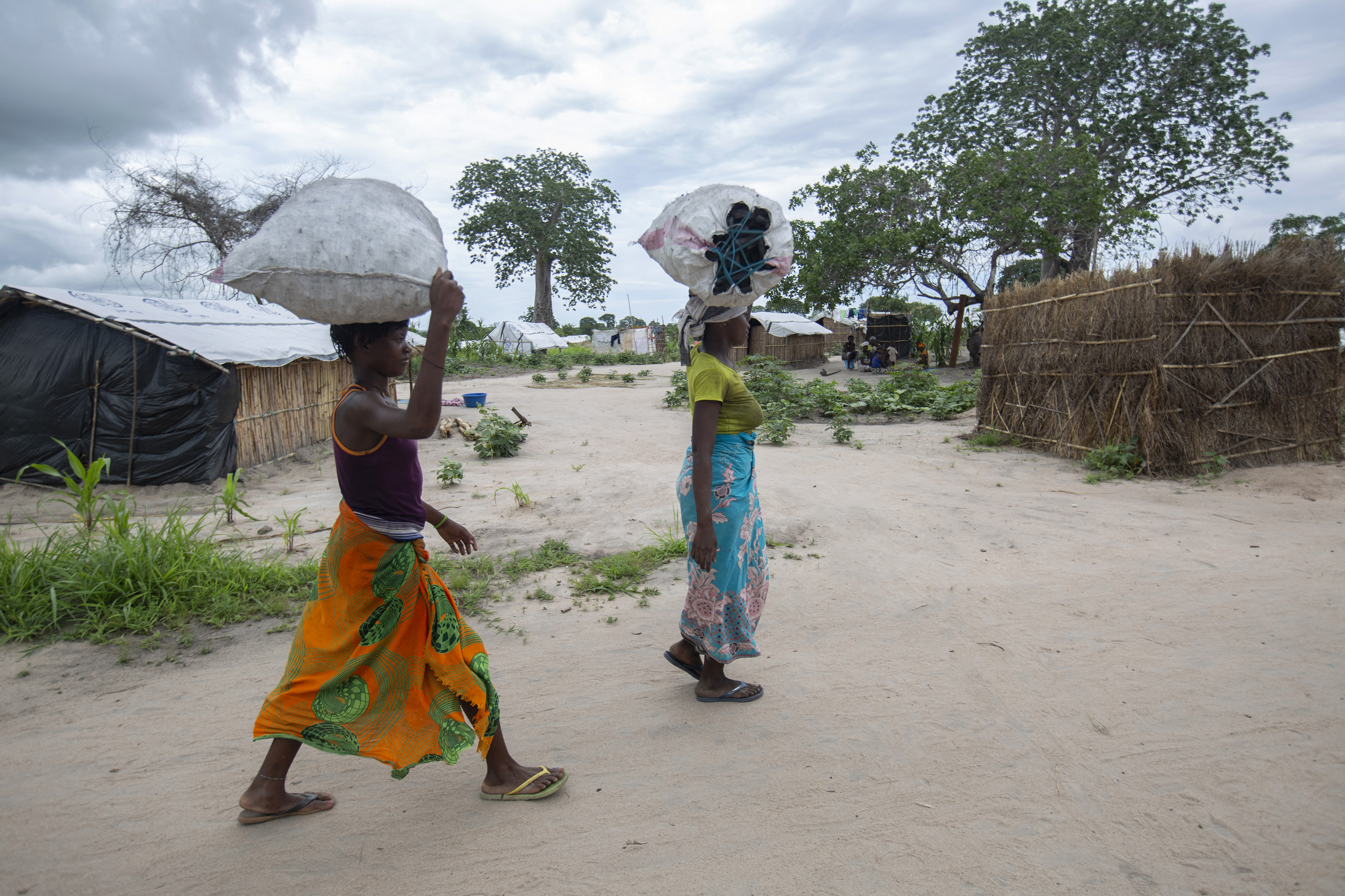 Women carry bags of charcoal at a centre for internally displaced persons in the Tara Tara district of Matuge, northern Mozambique on February 24, 2021 [File: AFP/Alfredo Zuniga]