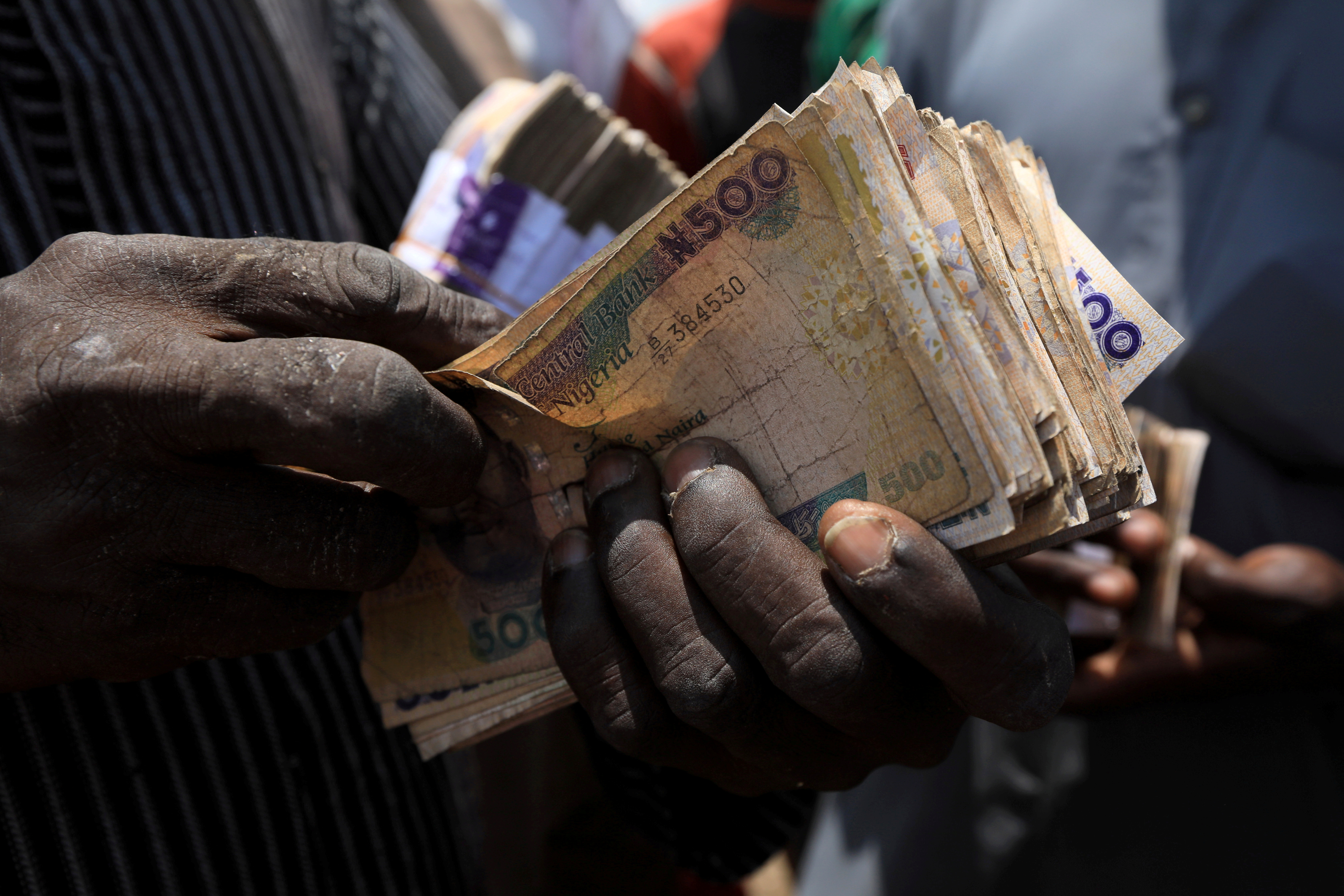 A man carries Nigerian naira banknotes at a livestock market in Abuja, Nigeria