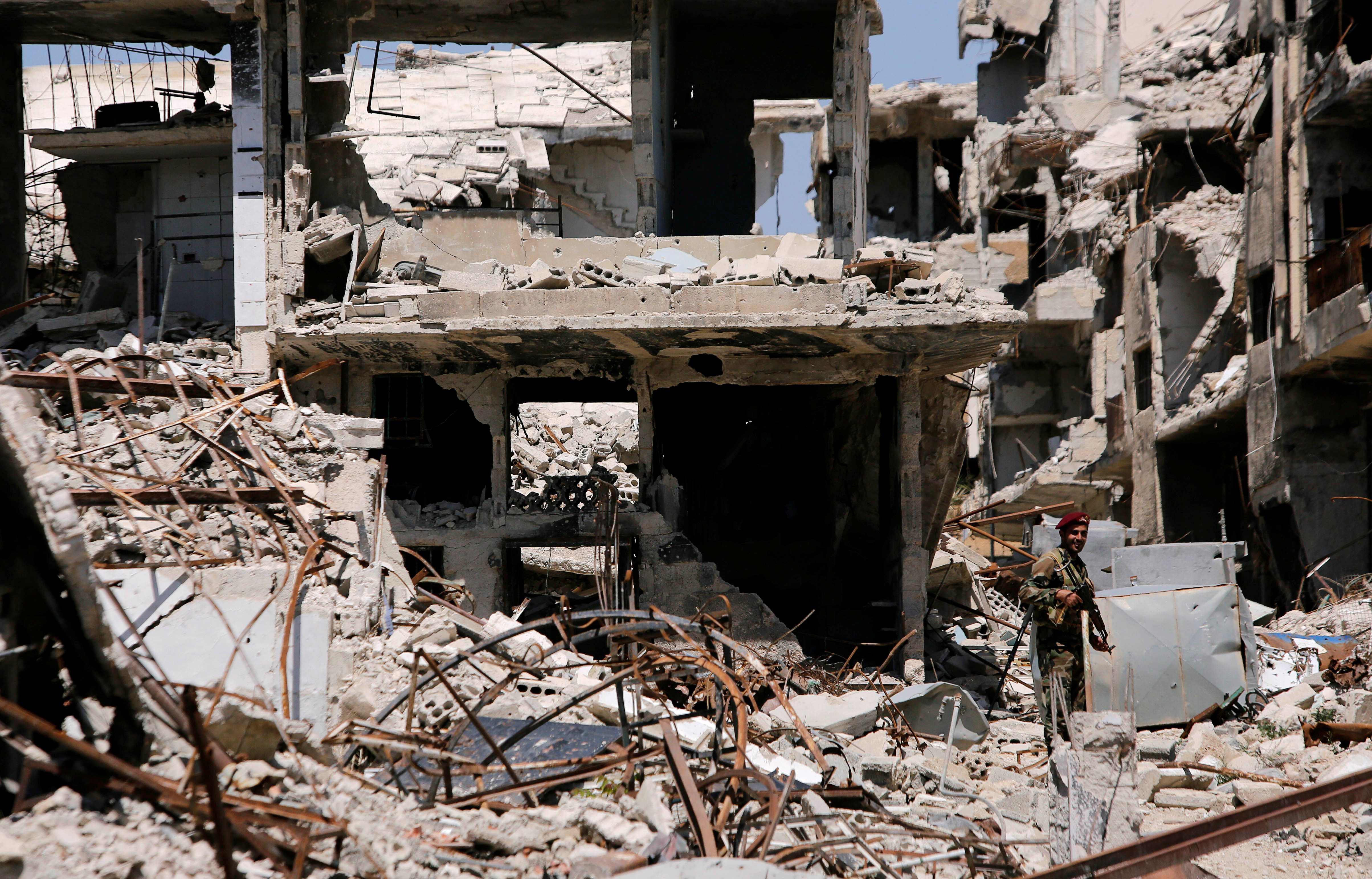 A member of Syrian forces stands guard in front of destroyed buildings in Jobar, eastern Ghouta, in Damascus, Syria, April 2, 2018