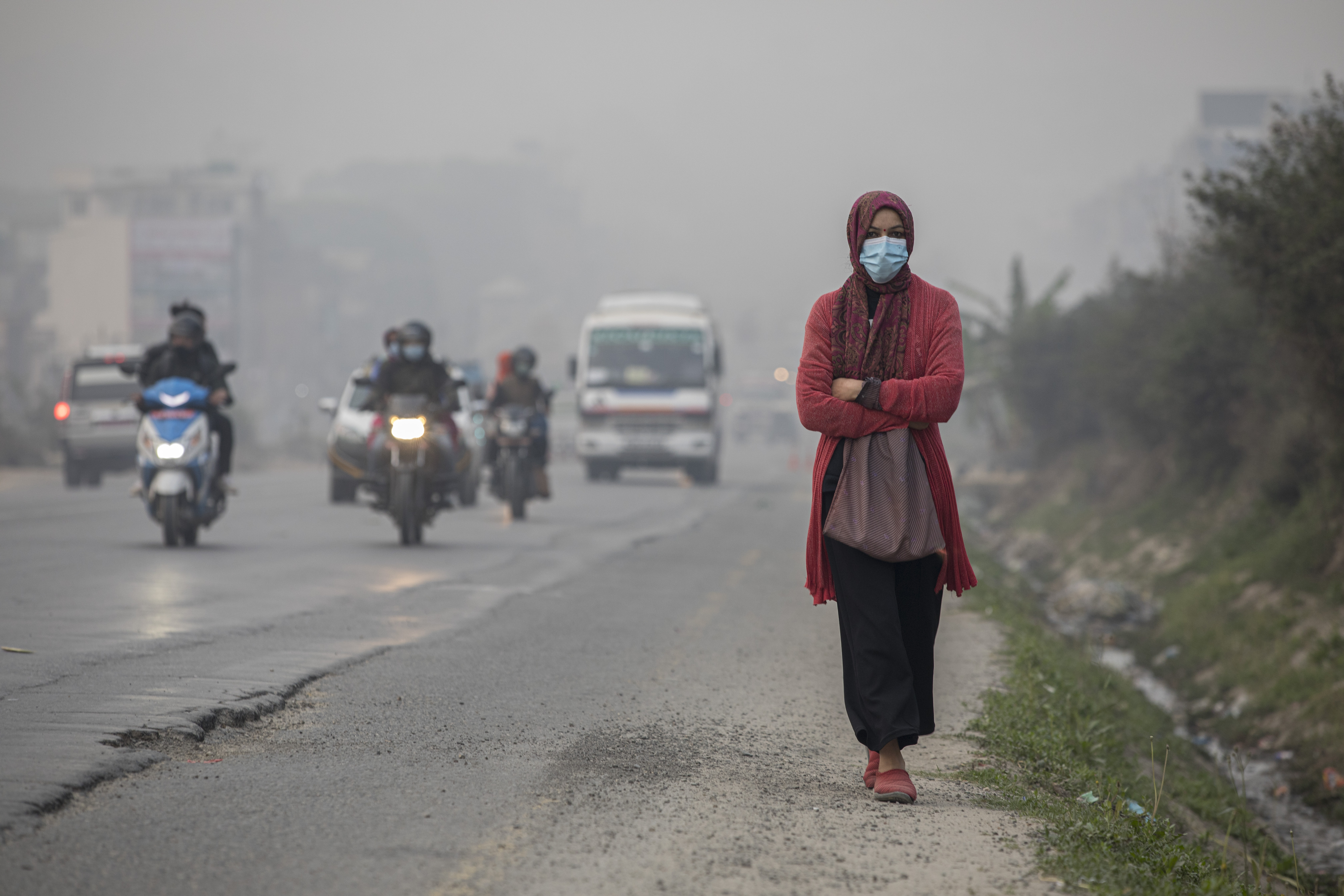 A person wearing face mask walks during a smoggy day in Kathmandu, Nepal