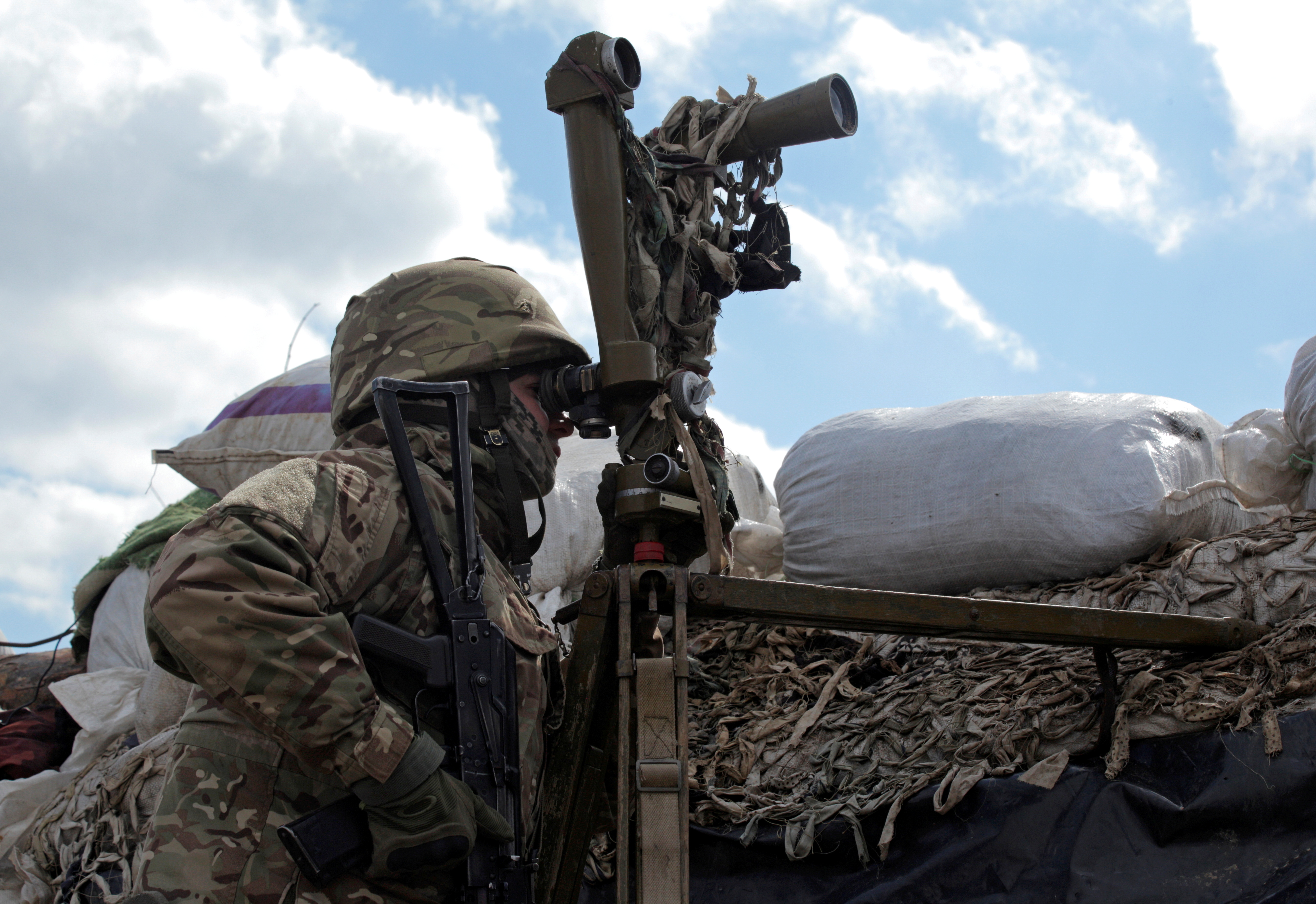 A service member of the Ukrainian armed forces is seen using a periscope while observing the area at fighting positions on the line of separation near the rebel-controlled city of Donetsk, Ukraine