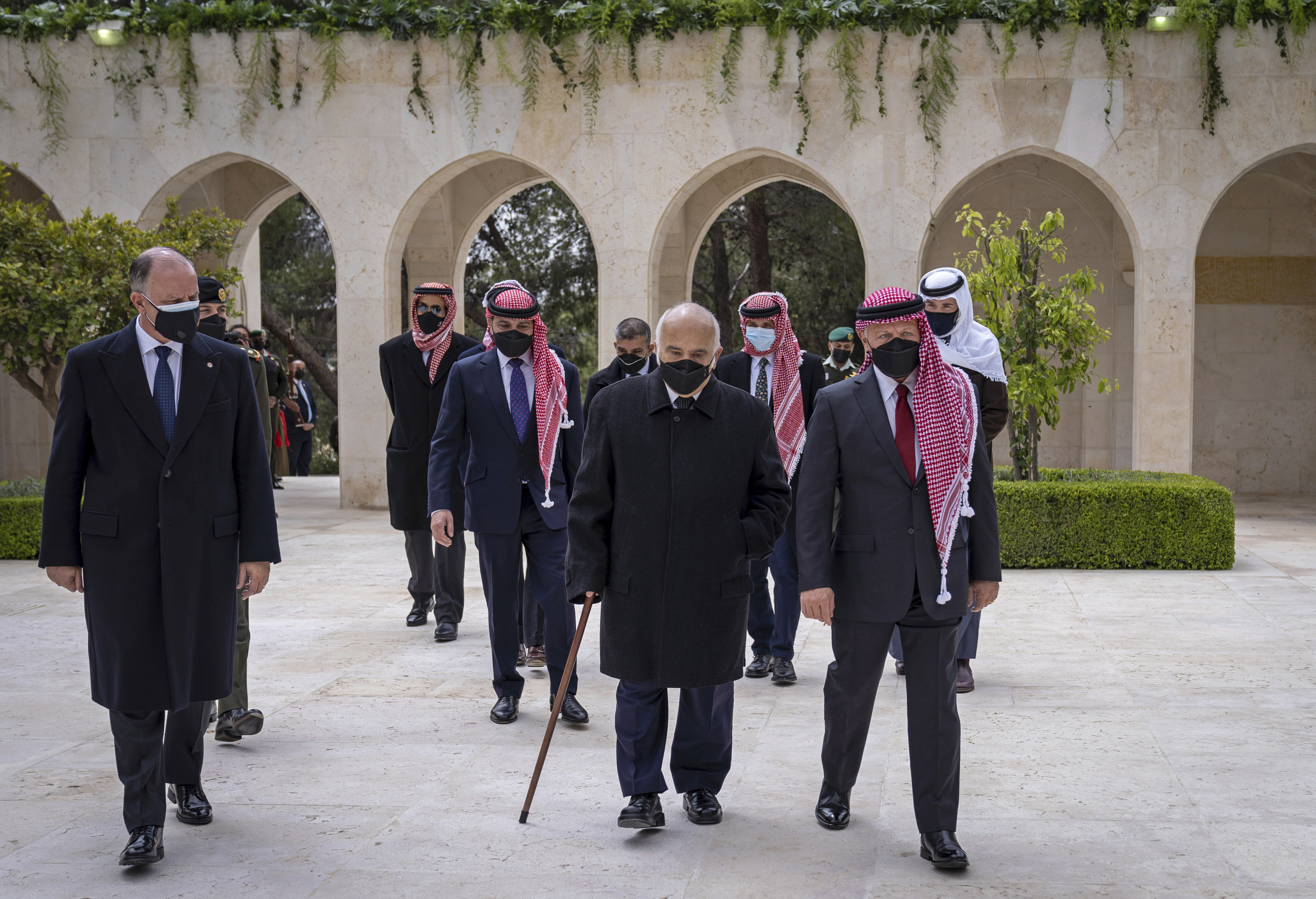 Jordan’s King Abdullah II, second right, Prince Hamzah bin Al Hussein, fourth right in blue mask, Prince Hassan bin Talal, fifth right, and others arriving to visit the tombs of former kings in Amman [File: Royal Court Twitter Account via AP]