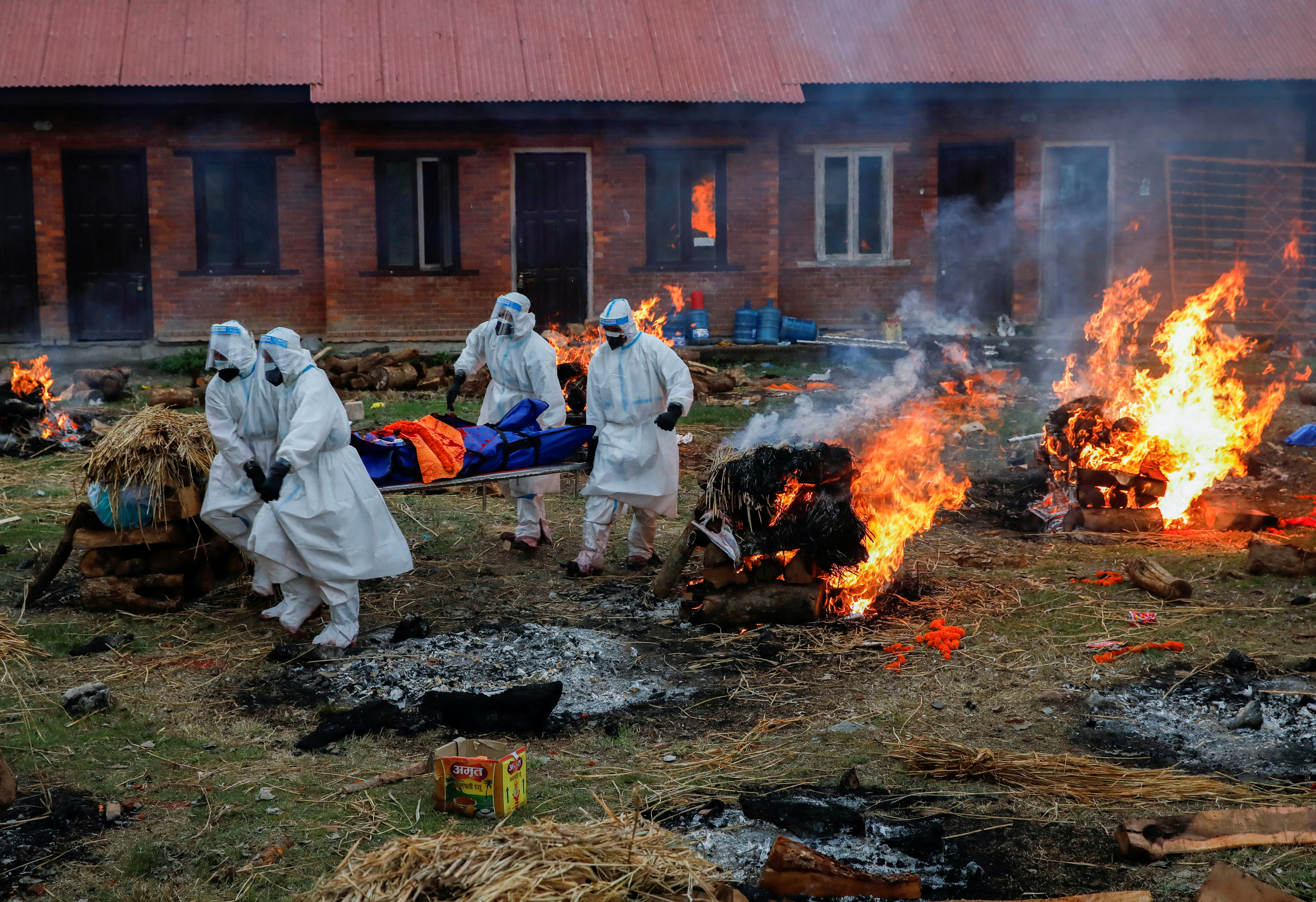 Members of the Nepali Army, wearing PPE, carry the body of a coronavirus victim at a crematorium in Kathmandu [File: Navesh Chitrakar/Reuters]