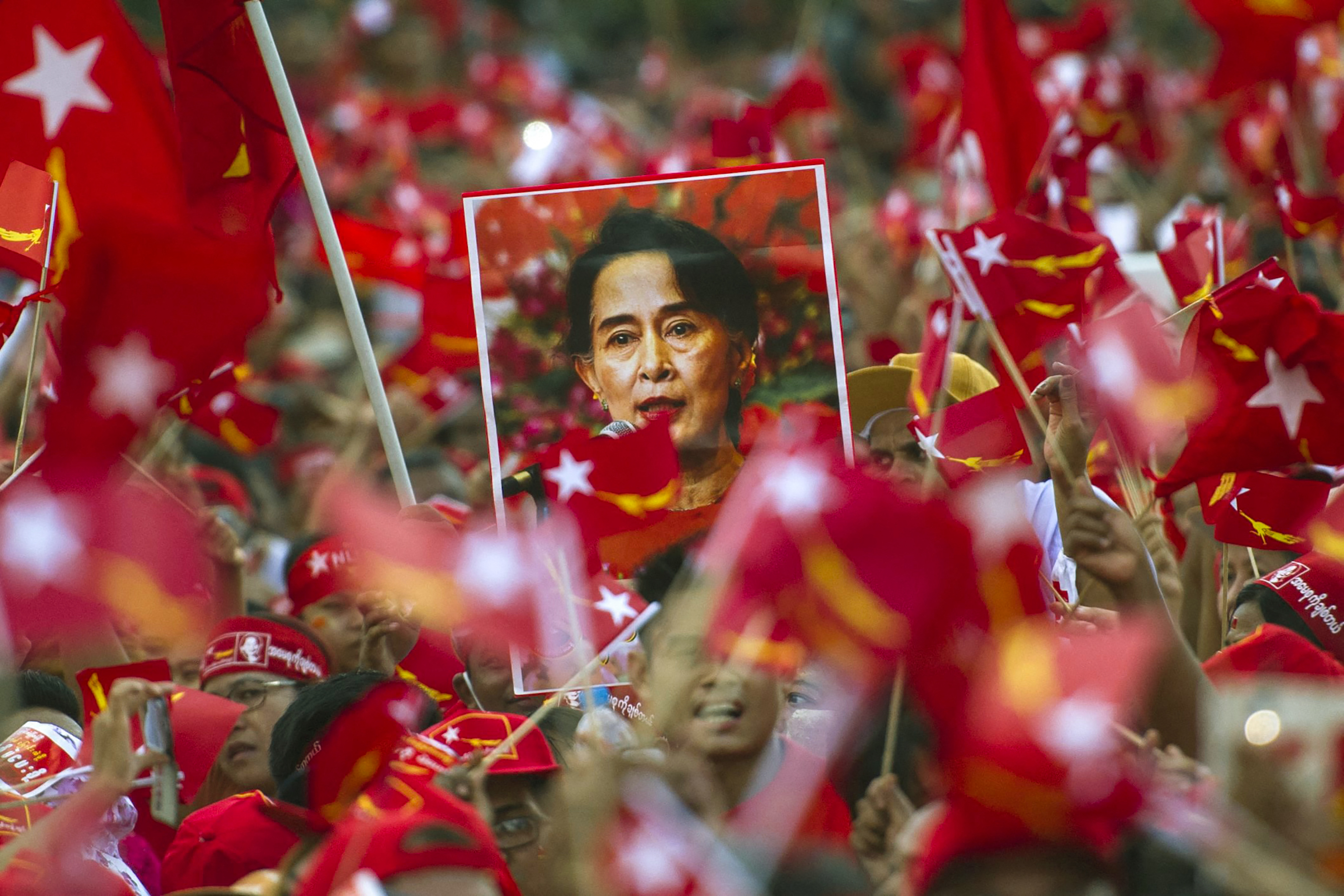 (FILES) In this file photo taken on November 1, 2015, supporters of opposition leader Aung San Suu Kyi hold posters bearing her image as they listen to her speak during a campaign rally for the National League for Democracy (NLD) in Yangon. - Ousted Myanmar leader Aung San Suu Kyi will hear the first testimony against her in a junta court on June 14, 2021, more than four months after a military coup. (Photo by STR / AFP)