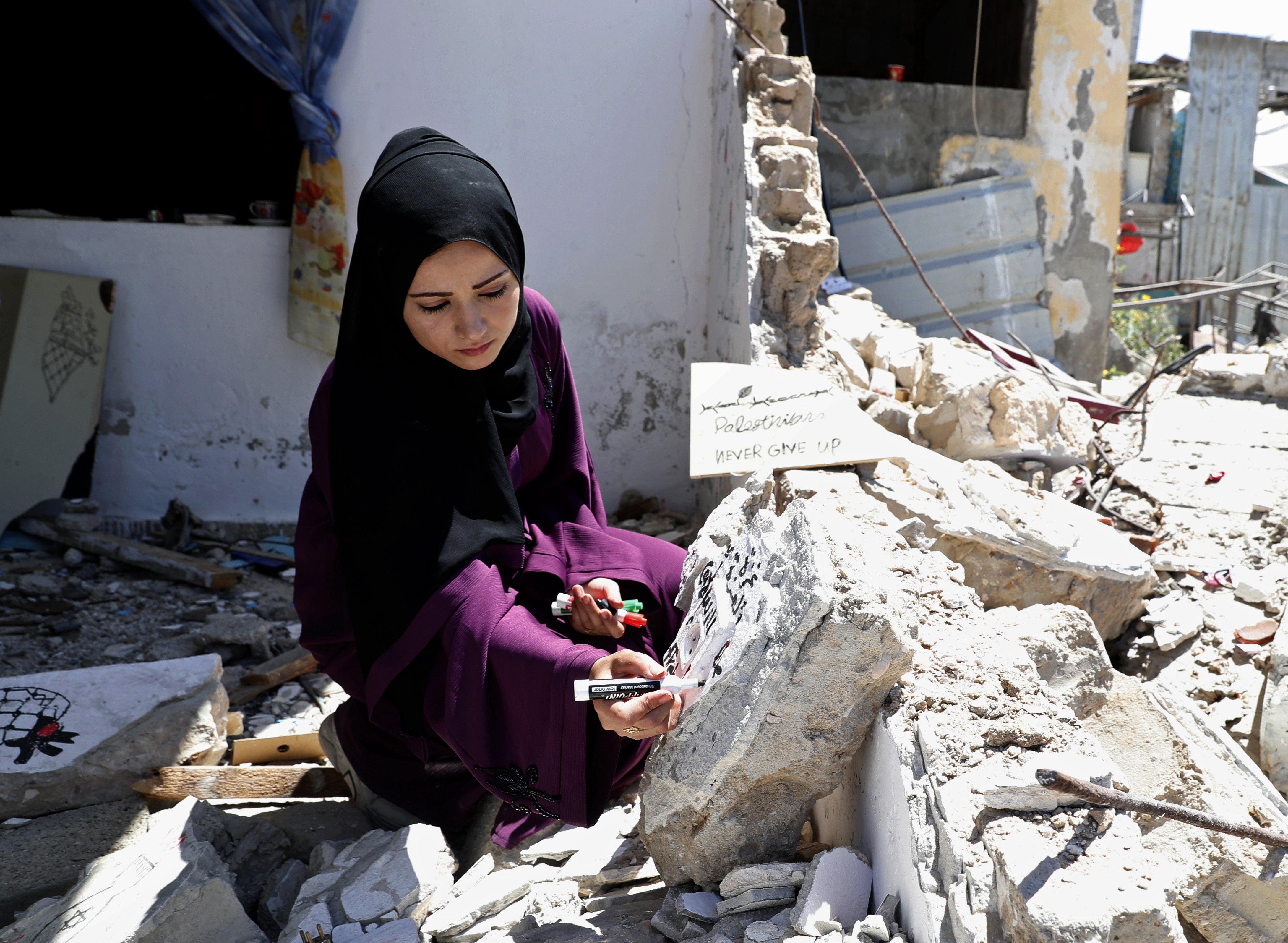 Artist Saja Moussa draws on broken tiles from her family's house in Rafah, southern Gaza Strip, damaged by Israeli bombing in May [Adel Hana/AP Photo]