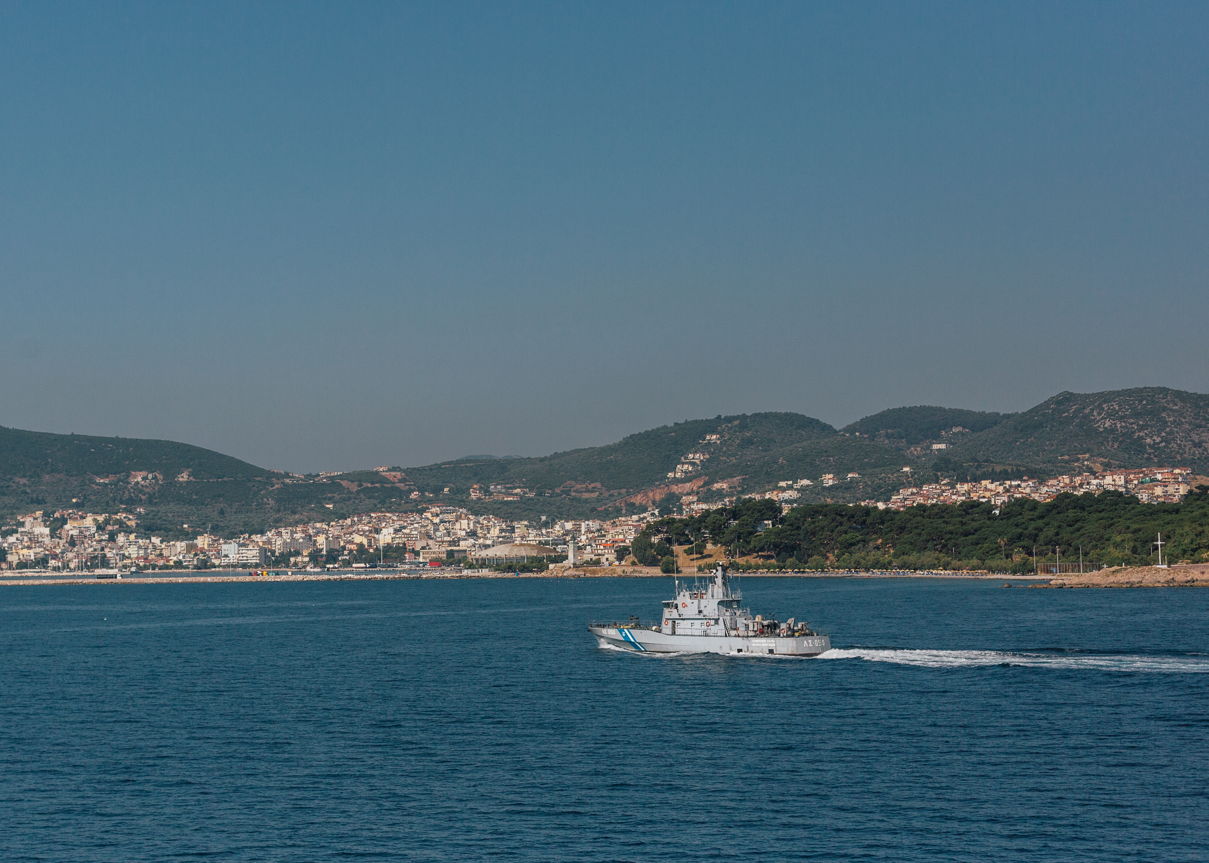 A Greek coast guard vessel sails in front of the shoreline of the city of Mytilini, Lesvos