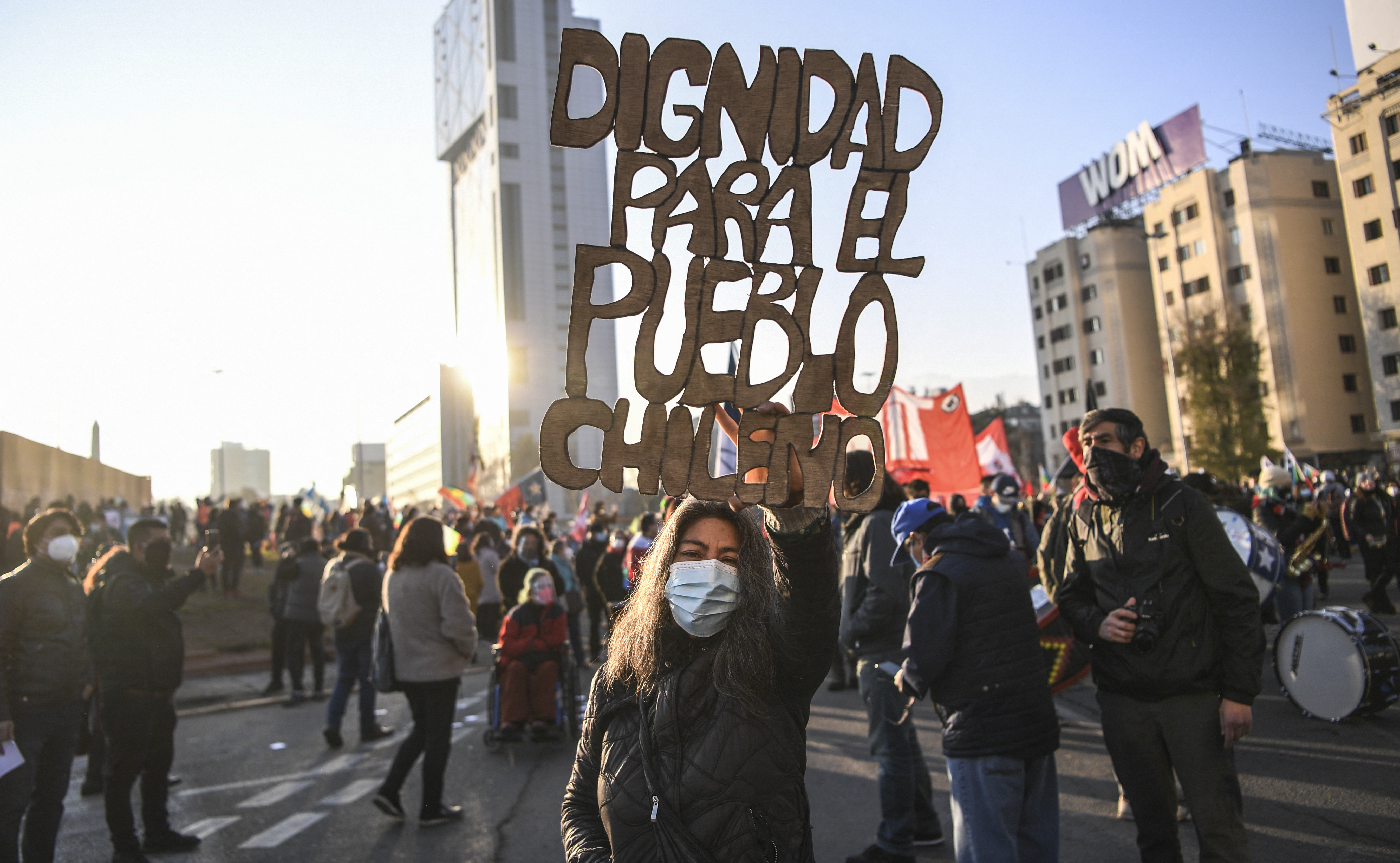 A demonstrator holds a sign reading 'Dignity for Chilean people' during a march towards the Chilean National Congress where the Constituent Assembly will be inaugurated in Santiago, on July 4 [Martin Bernetti/AFP]