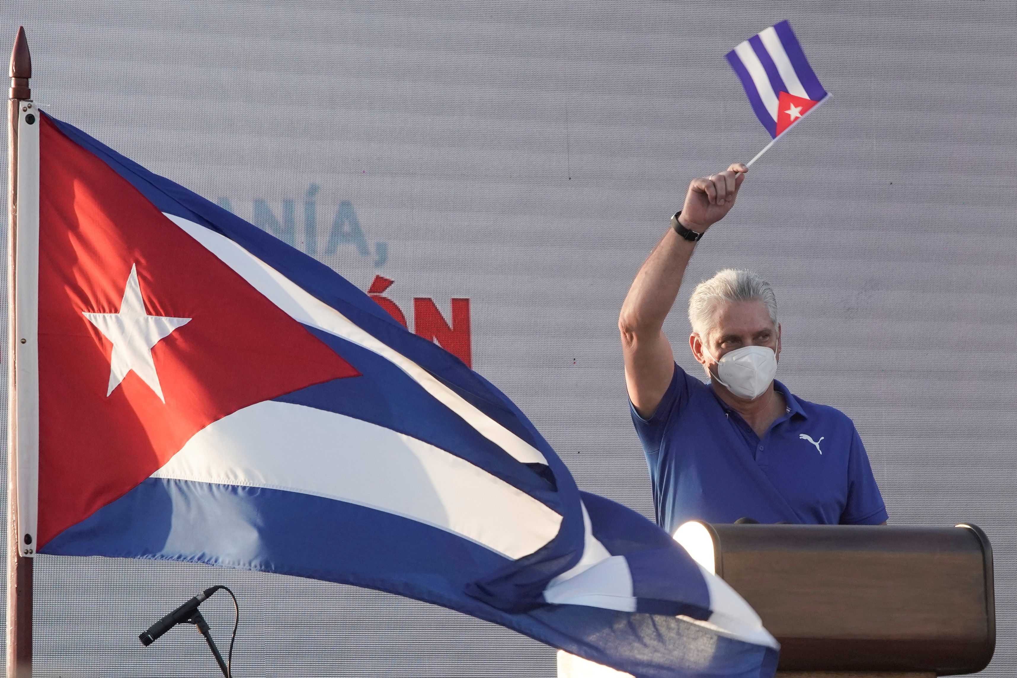 Cuban president waves a flag as he delivers remarks at an event