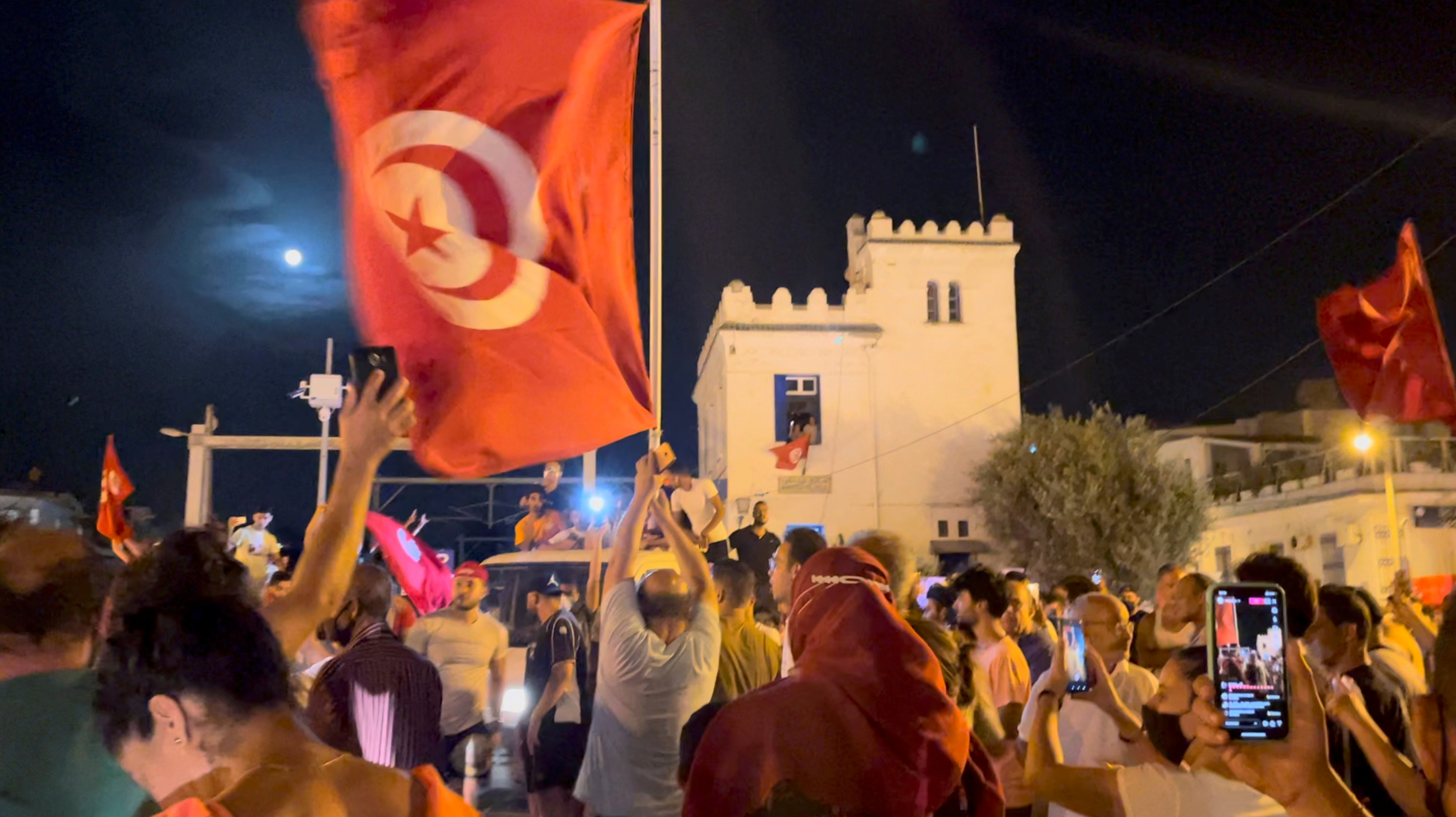 Crowds gather on the street after Tunisia's president suspended Parliament, in La Marsa, near Tunis, Tunisia, July 26, 2021, in this still image obtained from a social media video. [Layli Foroudi/Reuters]