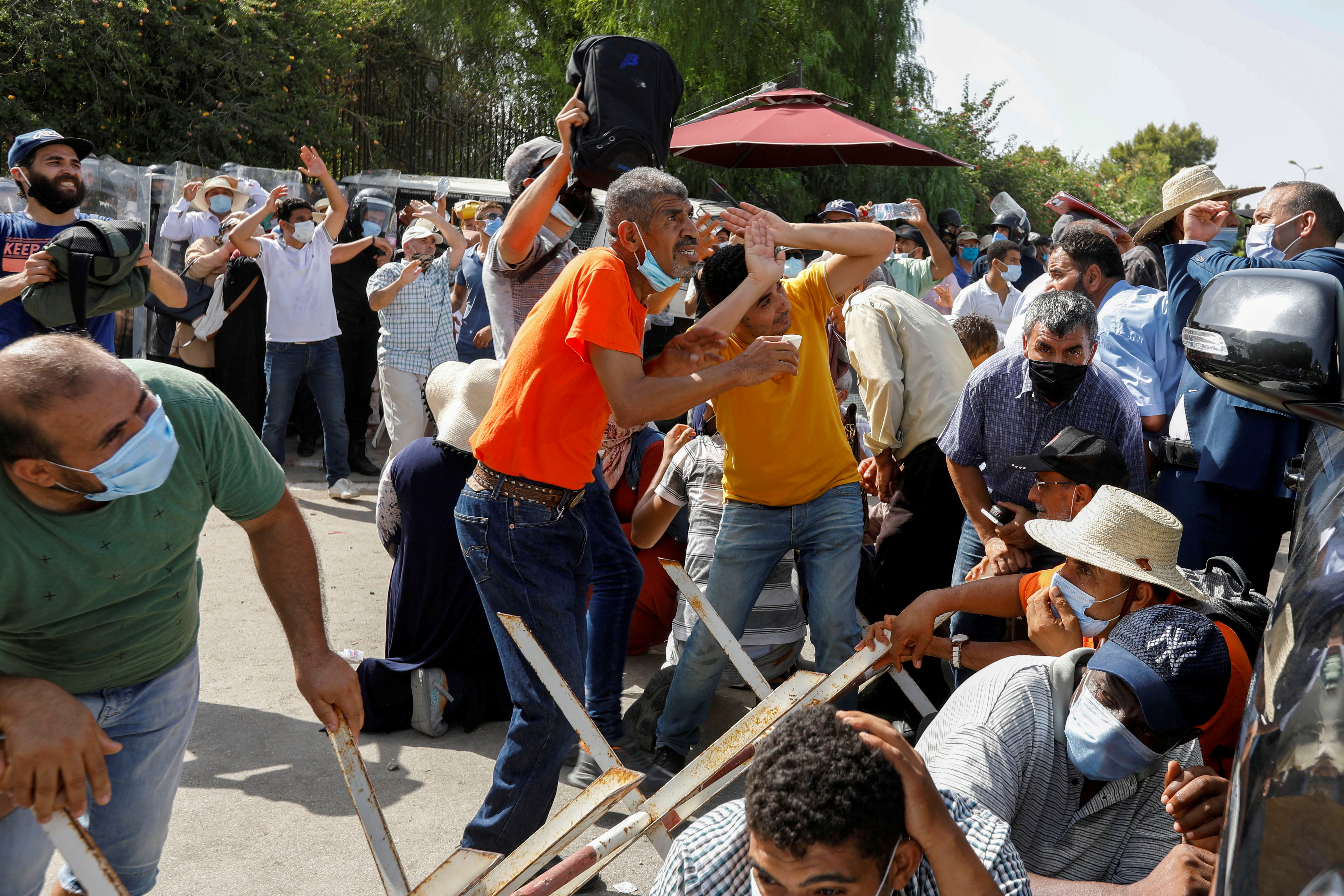 Supporters of Tunisia's biggest political party, Ennahda, take cover from stones thrown at them by supporters of President Kais Saied, outside the parliament building in Tunis, Tunisia July 26, 2021. [Zoubeir Souissi/Reuters]