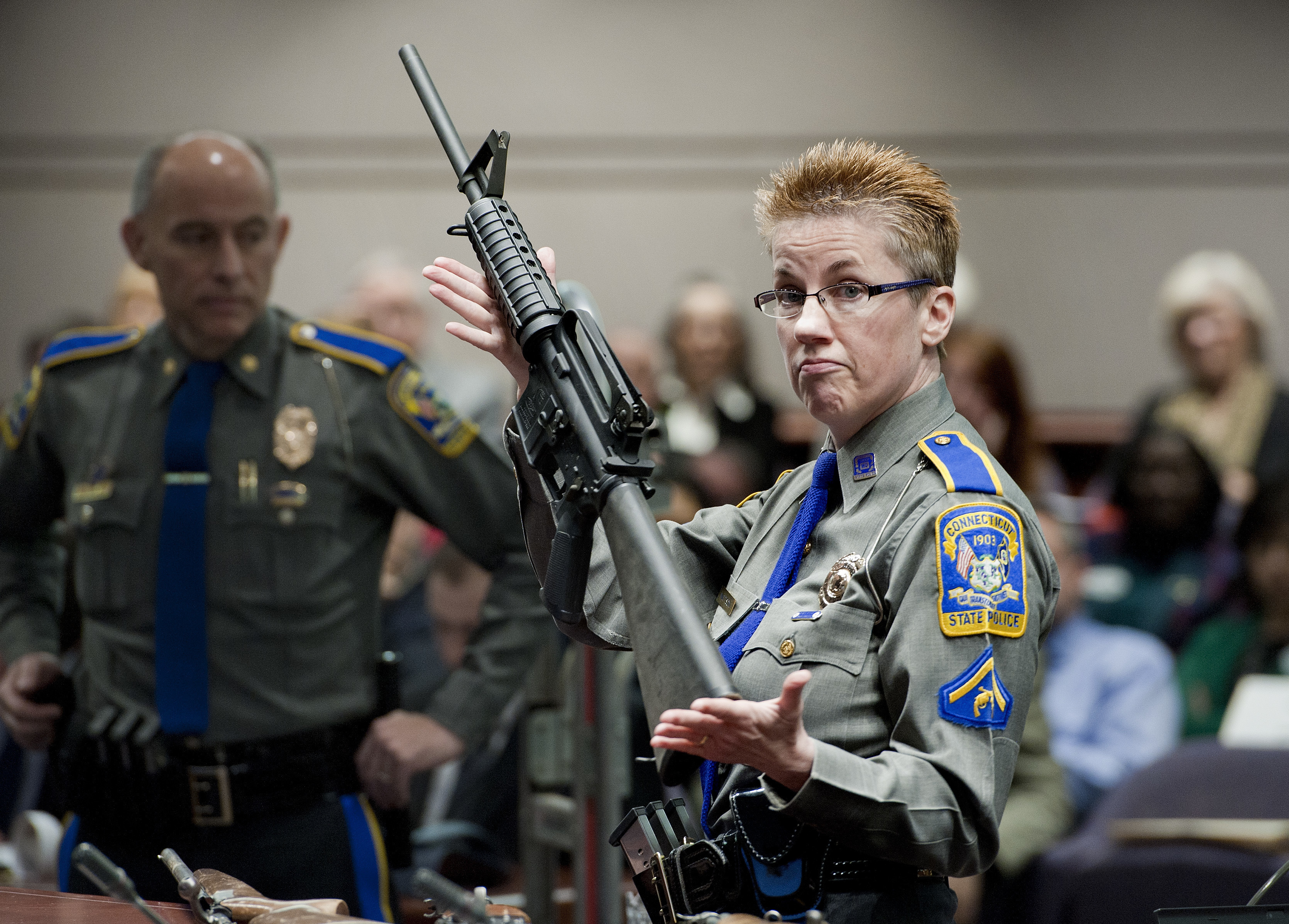 Connecticut State Police Detective Barbara Mattson holds up a Bushmaster AR-15 rifle, the same make and model of gun used by Adam Lanza in the Sandy Hook School shooting
